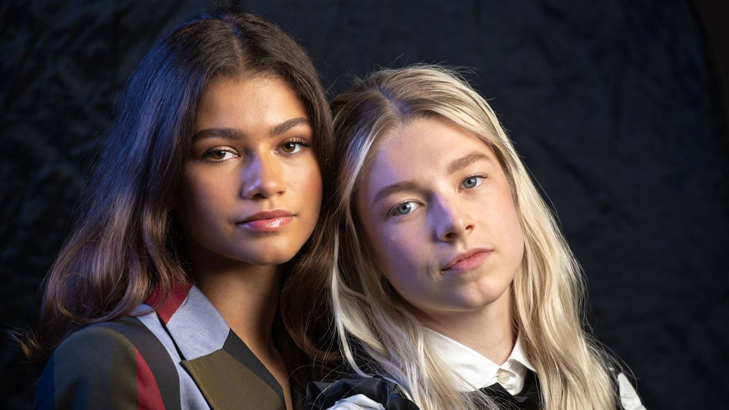 Hunter Schafer 桌布 壁紙 — 兩位髮色對比的年輕女性在深色紋理背景下直視鏡頭。