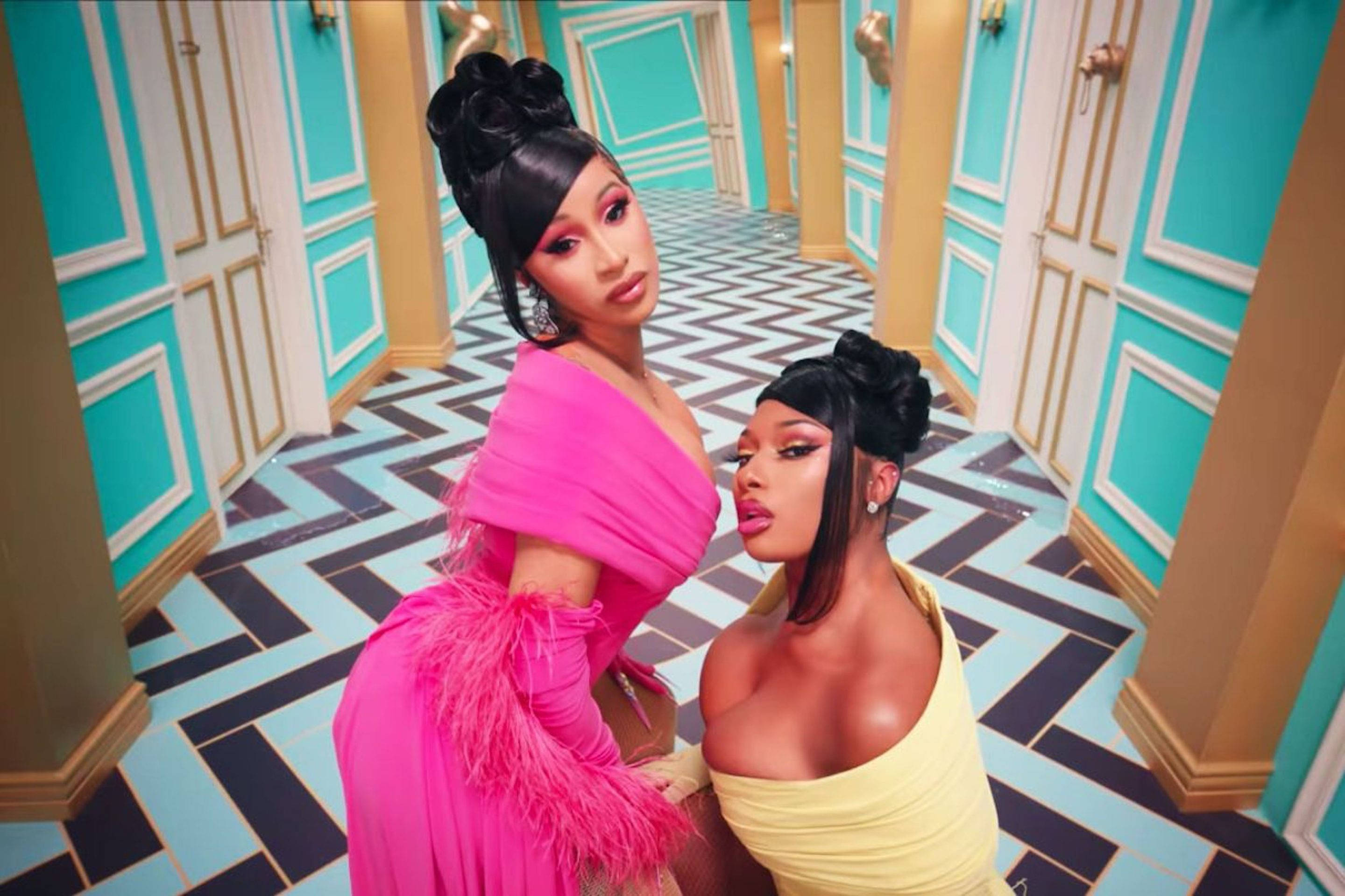 cardi 桌布 壁紙 — 兩位魅力女性身穿大膽的粉紅色和黃色連衣裙，在擁有綠松石牆壁和鋸齒形地板的豪華走廊中擺姿勢。