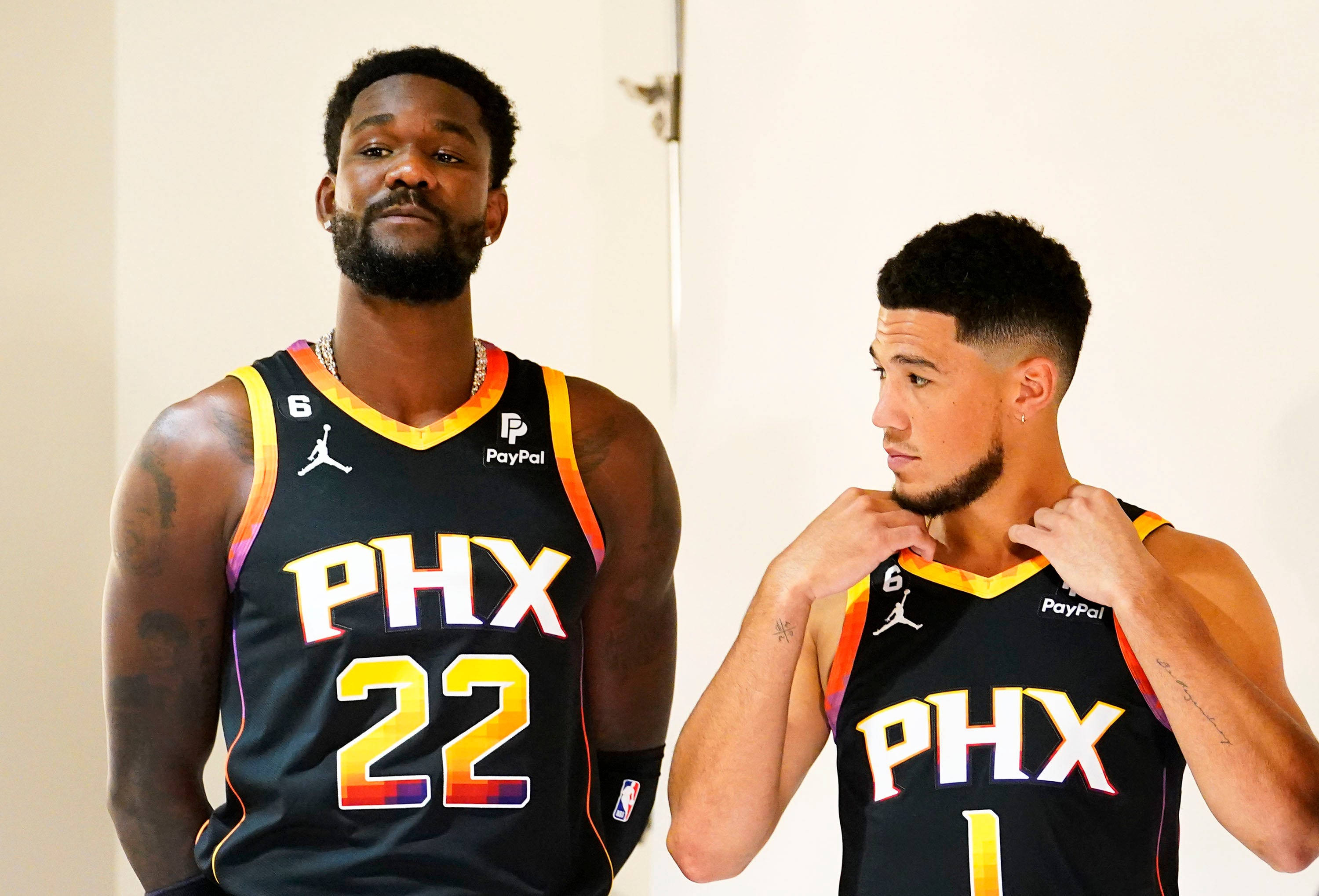 NBA 桌布 壁紙 — 兩位鳳凰城太陽隊籃球運動員身穿黑色球衣搭配彩虹邊，自信地站在純白牆前擺姿勢。