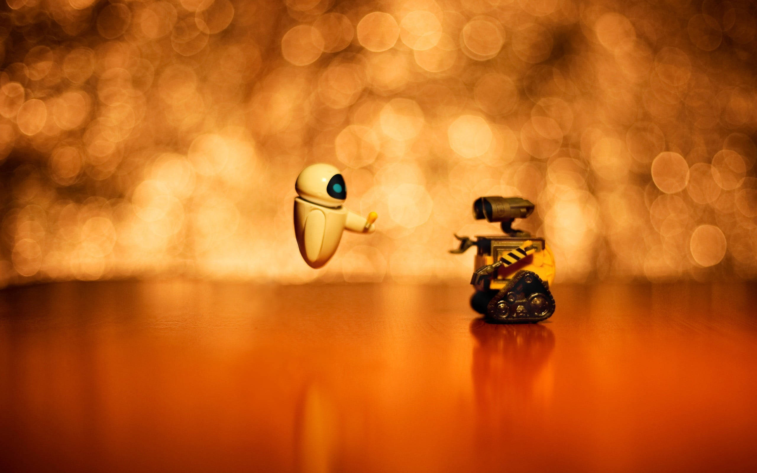E 桌布 壁紙 — 兩個 Pixar 機器人漂浮並站在木質表面上，背景是溫暖的金色散景。