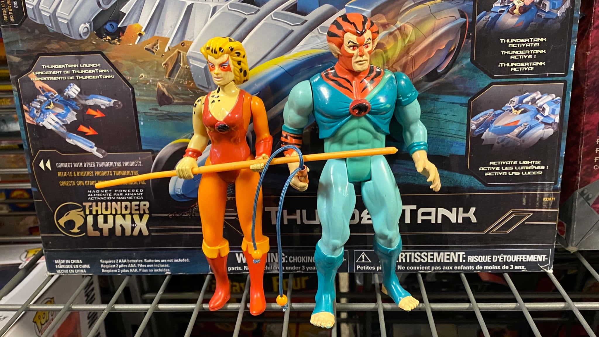 Exosquad 桌布 壁紙 — 兩個 ThunderCats 動作人偶站在貨架上，前面是色彩繽紛的包裝，上面有車輛和角色圖案。