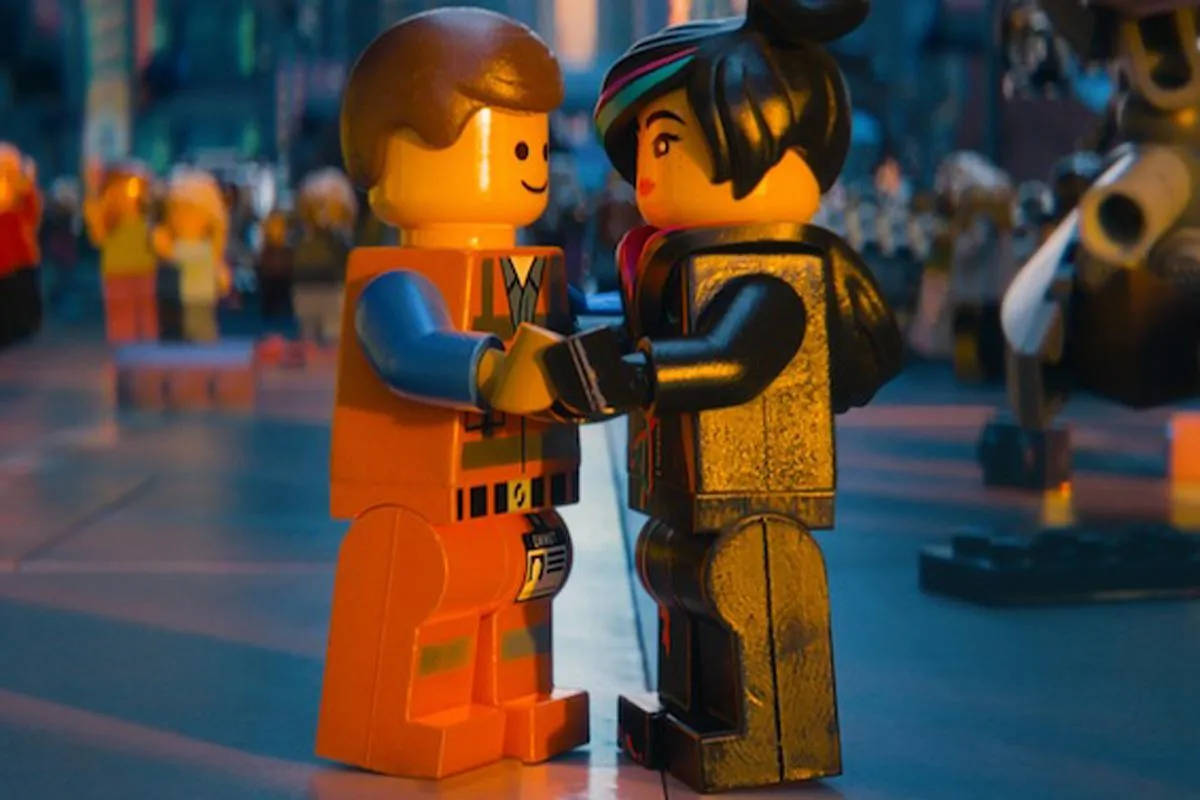 樂高 桌布 壁紙 — 兩個LEGO迷你人偶在溫暖燈光的城市街道場景中牽手，背景人物模糊。