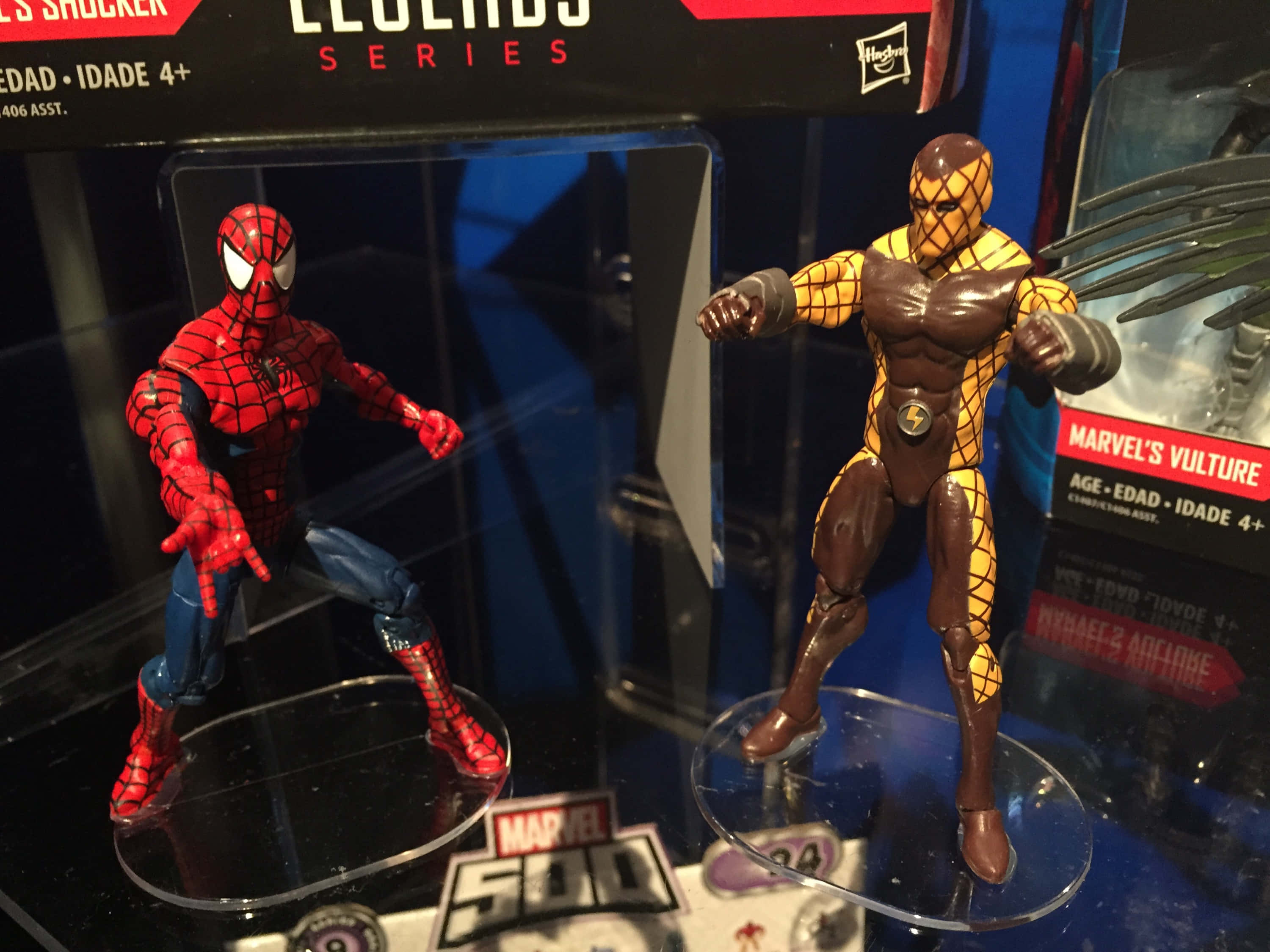 The Shocker 桌布 壁紙 — 兩個Marvel可動人偶蜘蛛人與禿鷹站在透明底座上，包裝內品牌標示清晰可見。