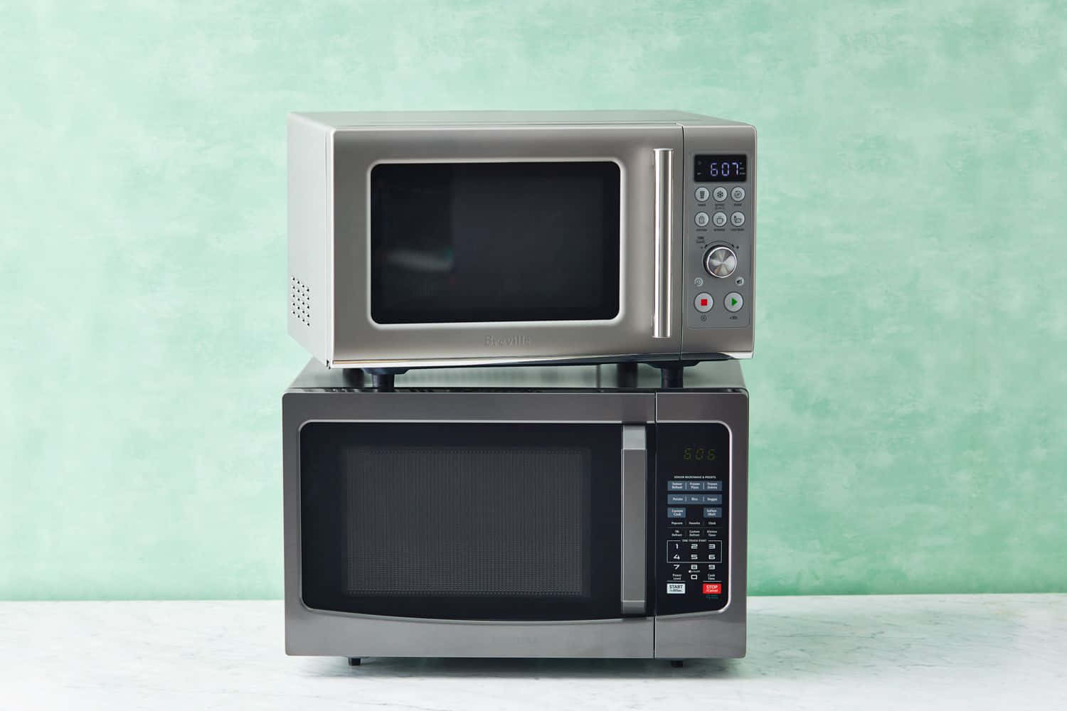 Microwave 桌布 壁紙 — 兩個不鏽鋼微波爐一個疊在另一個上面，靠著薄荷綠紋理牆。