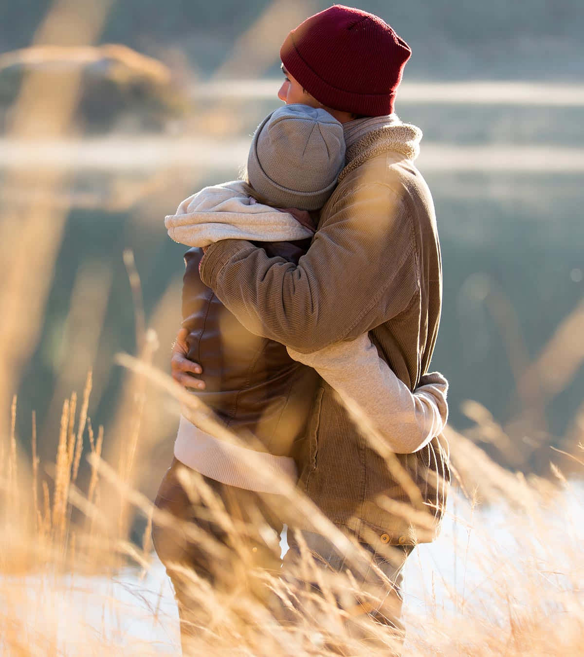 Hug 桌布 壁紙 — 兩個人在一片高高的金色草地上溫暖地擁抱，沐浴在柔和的金色時光陽光中。