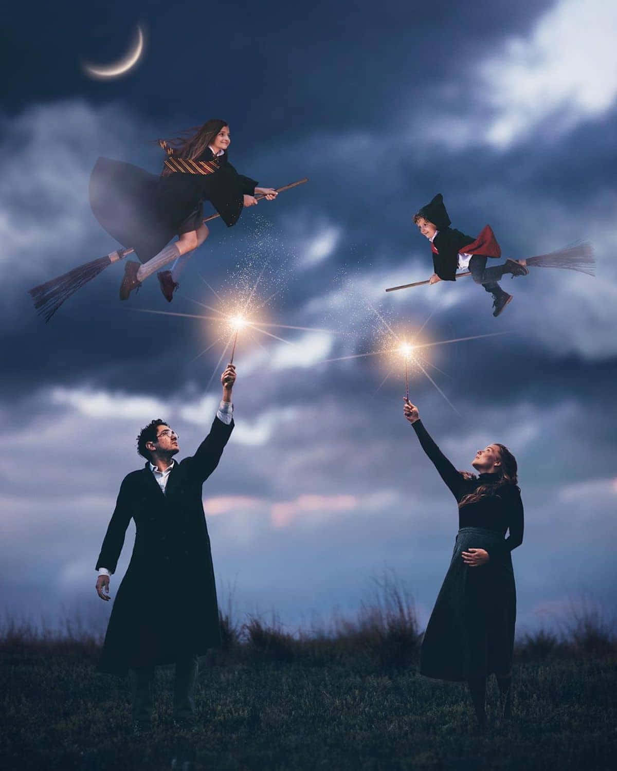 magical 桌布 壁紙 — 兩個人在地球上舉起魔杖向上，而兩個孩子在他們上方騎著掃帚飛翔，背景是月光照耀的多雲天空。
