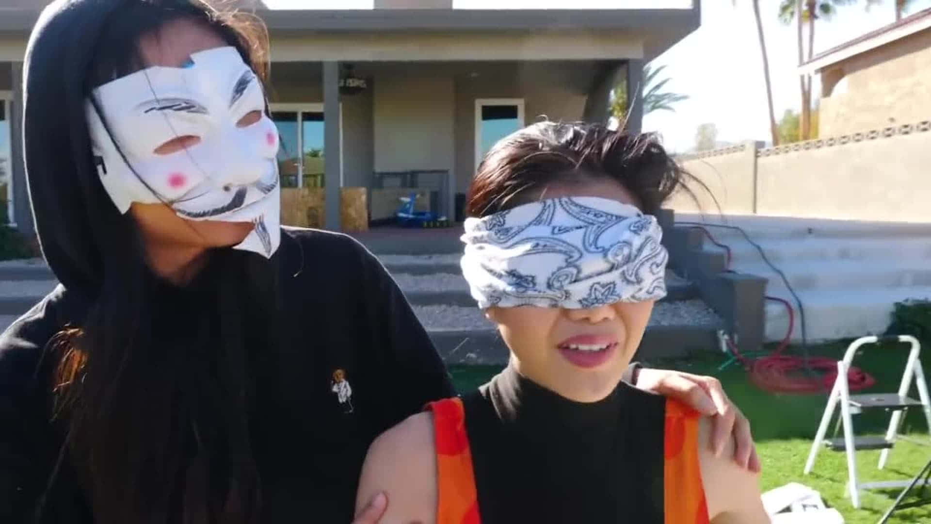 Woman 桌布 壁紙 — 兩個人在戶外，一人戴著白色蓋伊·福克斯面具，另一人用圖案頭巾矇住眼睛。