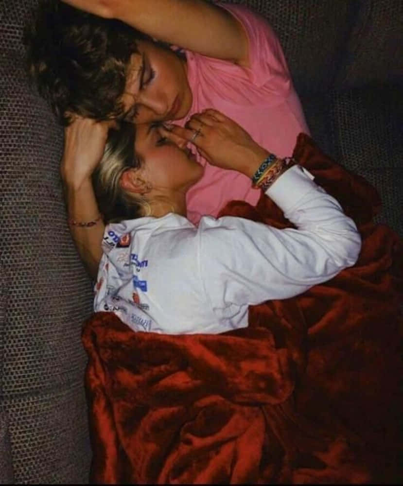 Girlfriend And Boyfriend 桌布 壁紙 — 兩個人在昏暗燈光下，親密地躺在沙發上，裹著一條柔軟的紅色毯子。