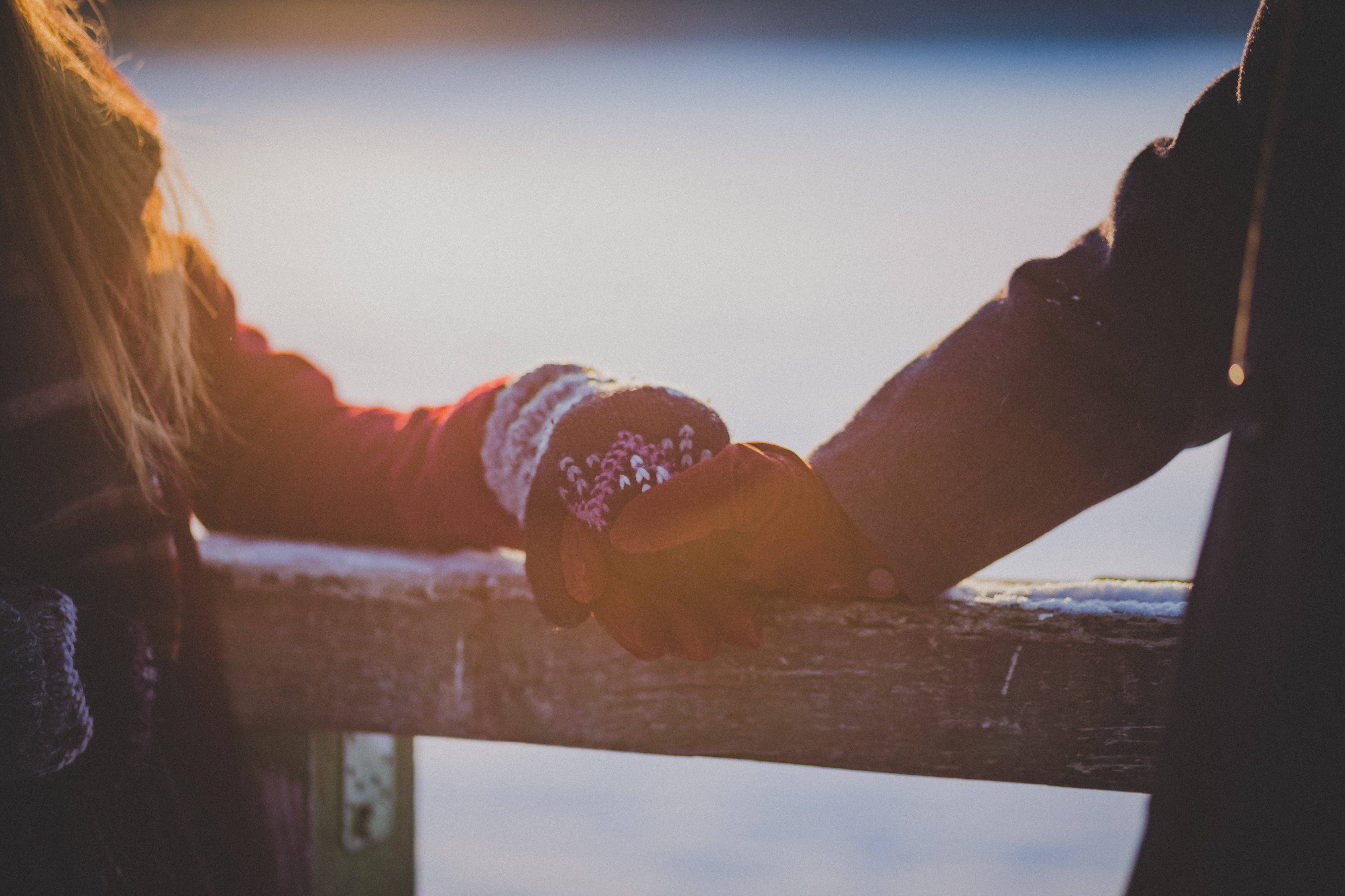 Love And Friendship 桌布 壁紙 — 兩個人在木欄杆上握著手，金色陽光溫暖地照在他們交纏的手指上。