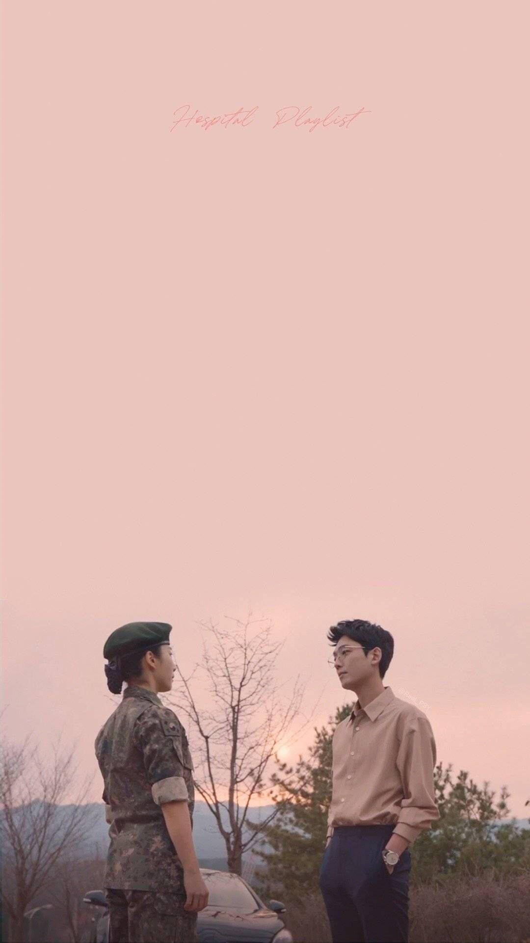 Playlist 桌布 壁紙 — 兩個人在柔和的粉紅色日落景觀中面對面站立，周圍有光禿禿的樹木和遠方的山丘。