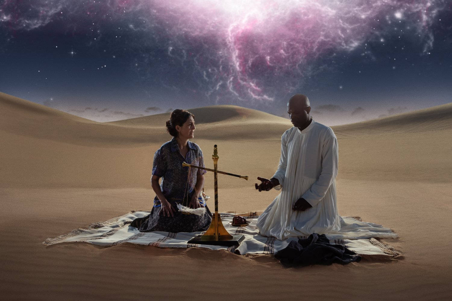 Gods 桌布 壁紙 — 兩個人在沙漠中跪在圖案地毯上，上方是充滿旋轉粉紅和紫色星雲的鮮豔宇宙天空。