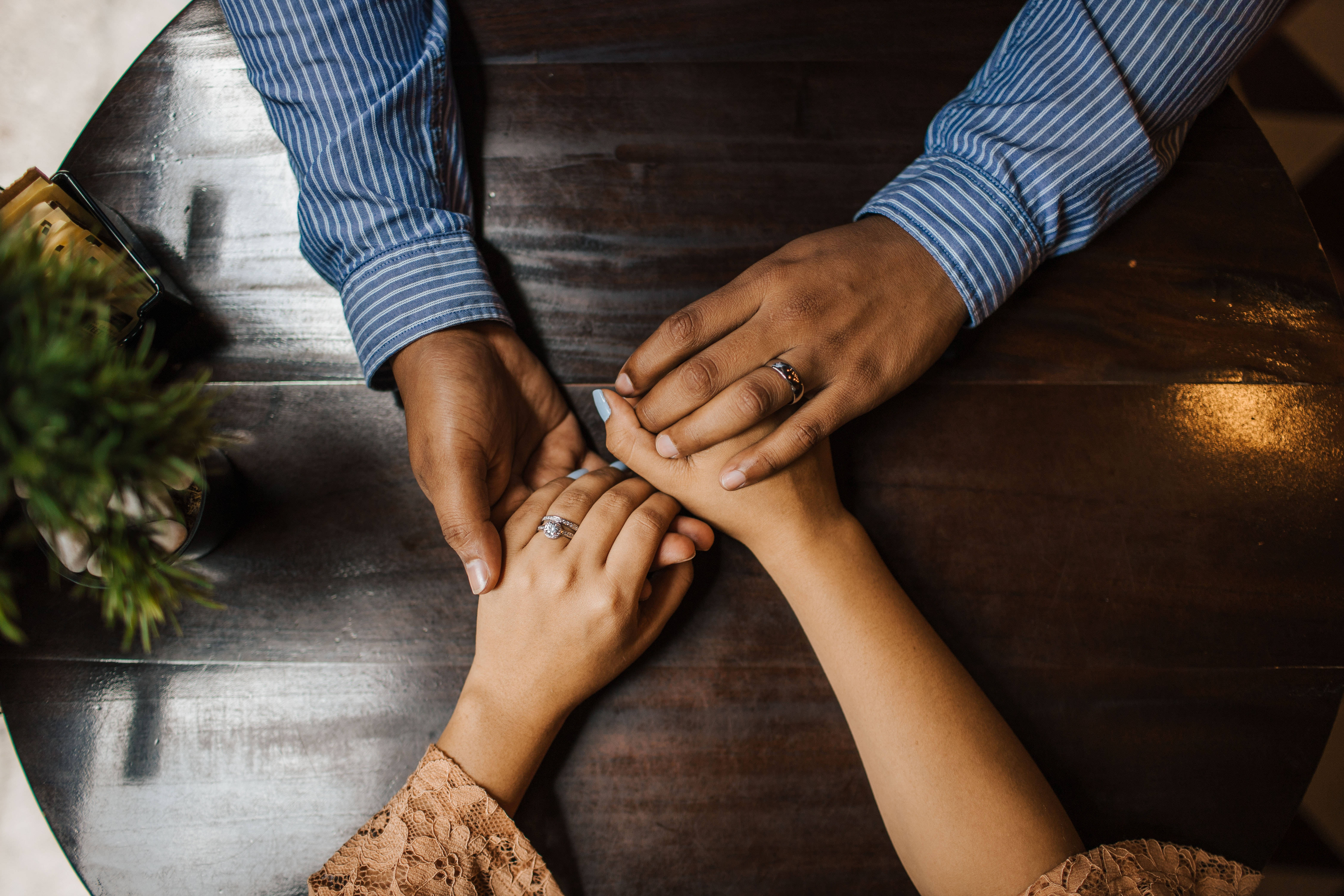 Couple Hands 桌布 壁紙 — 兩個人在深色木桌上牽手，手指上可見結婚戒指。