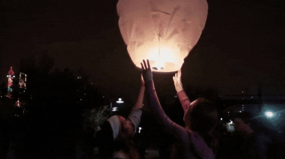 Best Friends Forever 桌布 壁紙 — 兩個人在遠處城市景觀上方的黑暗夜空中釋放一個發光的天燈。