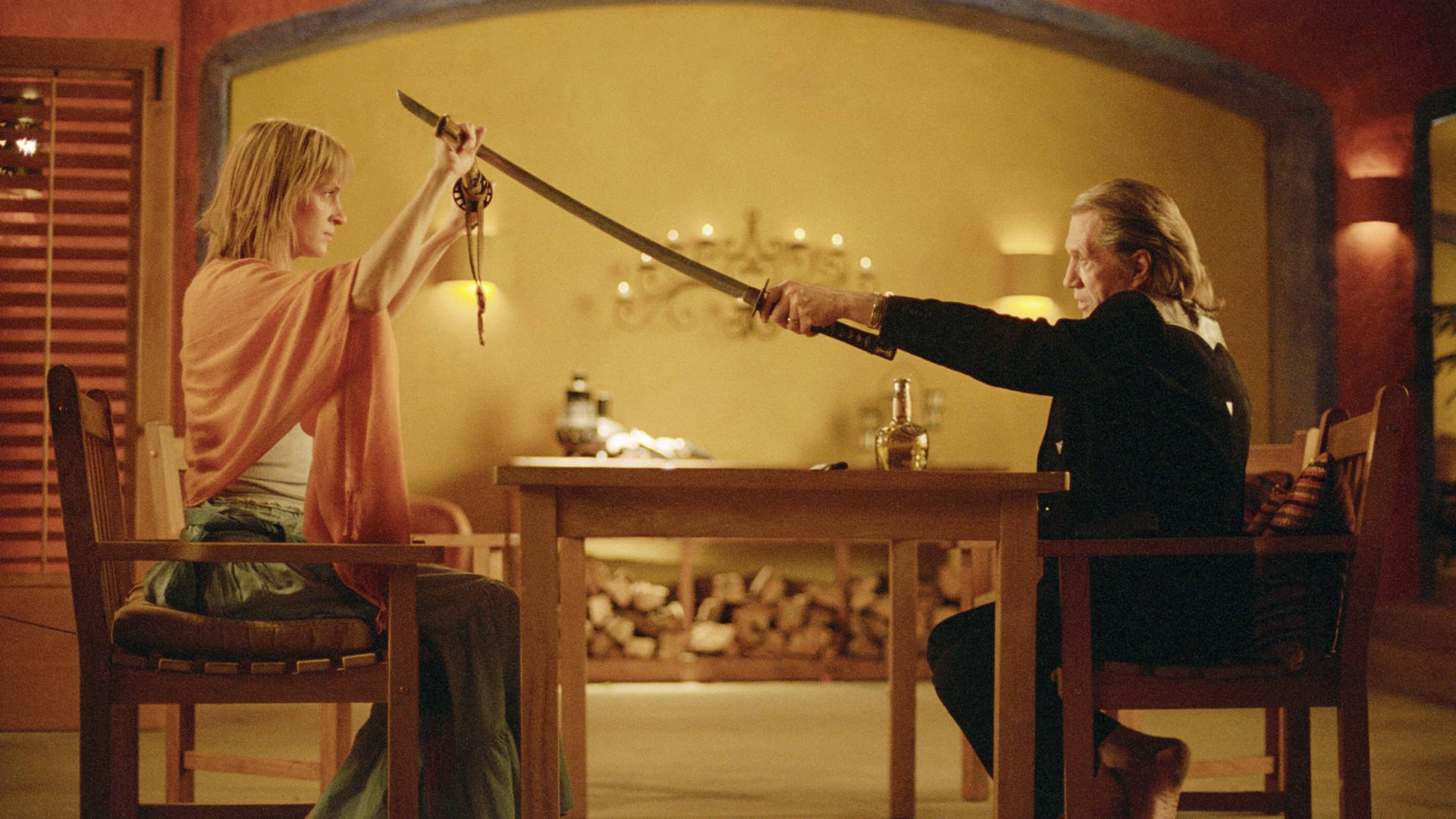 Kill Bill 桌布 壁紙 — 兩個人坐在一張木桌的兩邊，身處一個燈光溫暖的房間，正在進行緊張的劍術對決，劍刃交鋒。