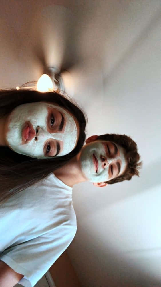 Girlfriend And Boyfriend 桌布 壁紙 — 兩個人戴著白色口罩在柔和光線的室內空間中對著鏡頭頑皮地微笑。