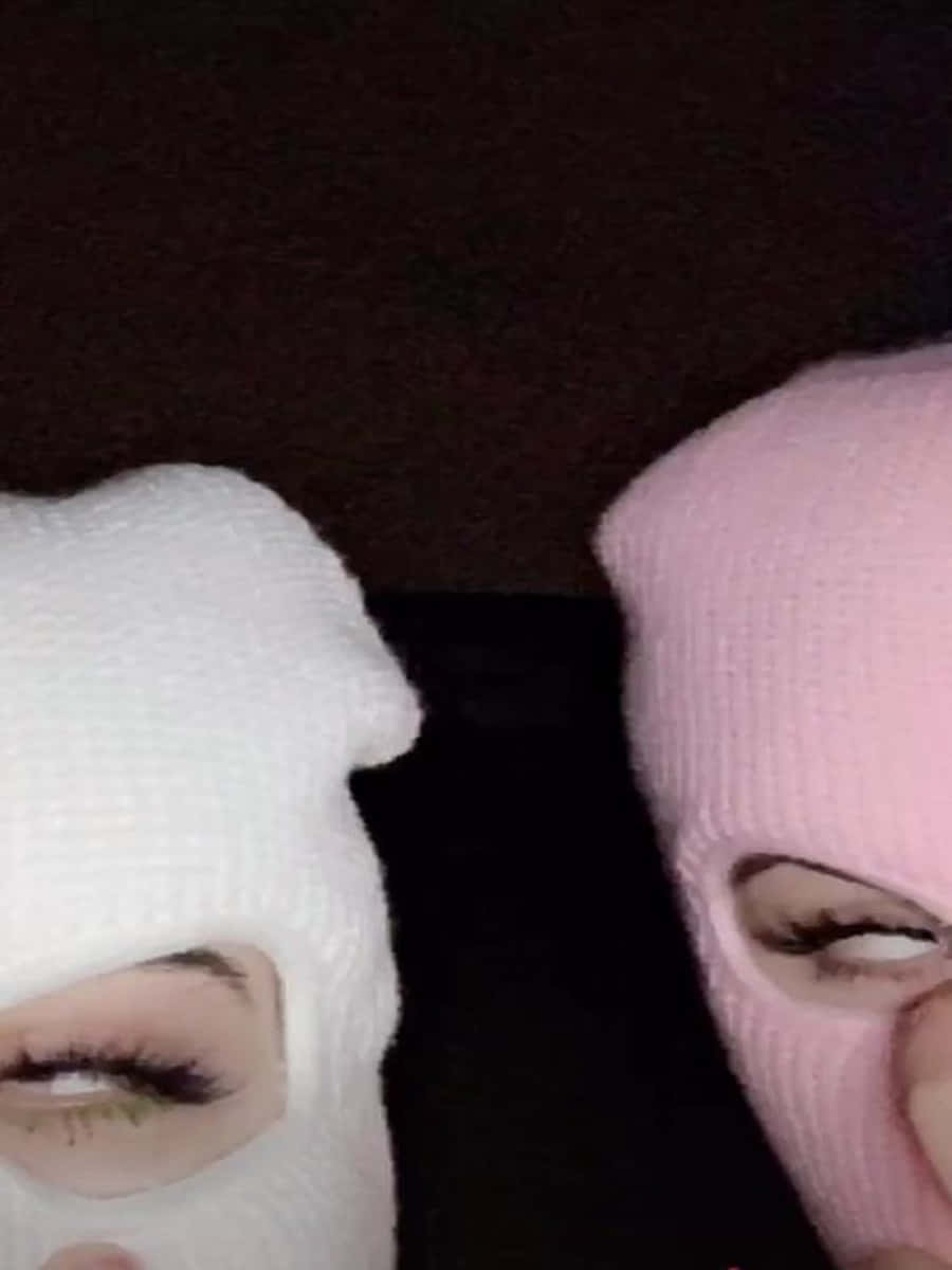 Ski Mask Girl 桌布 壁紙 — 兩個人戴著白色和粉紅色針織巴拉克拉法帽，在黑暗背景下只露出眼睛。