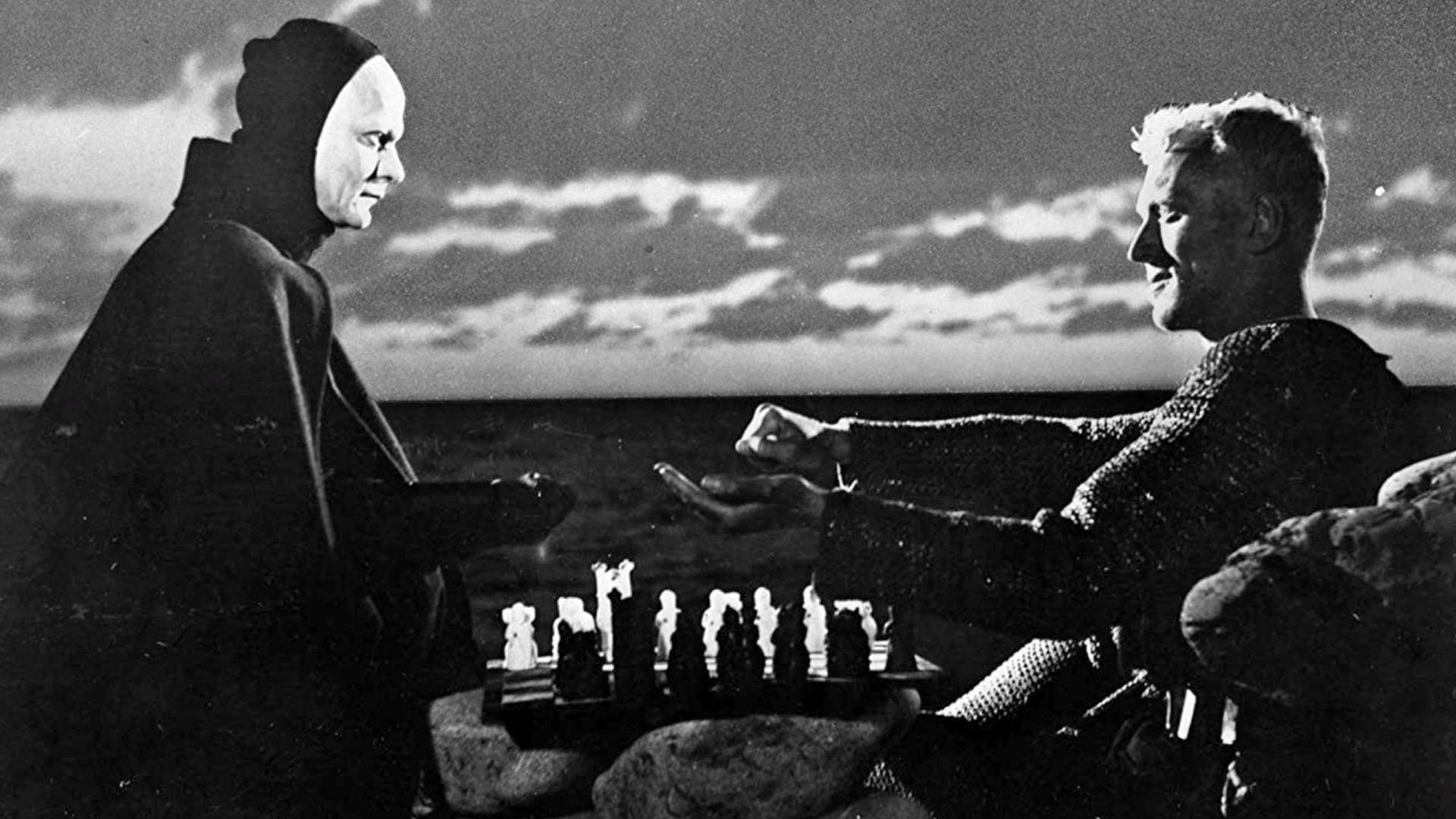 兩個人在黃昏時分在海邊岩石上下棋，黑白風格。 — King Von 壁紙