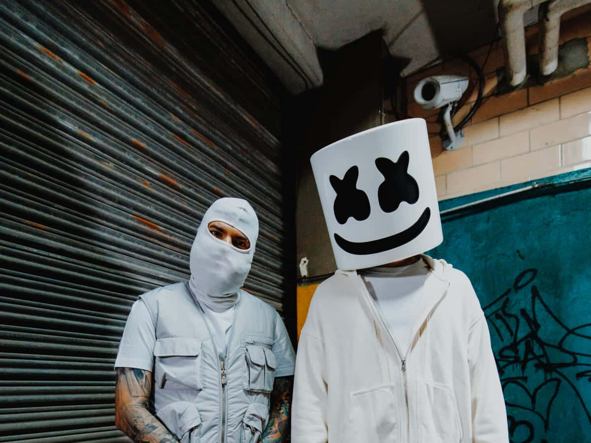 Marshmello 動態圖 桌布 壁紙 — 兩個人物站在城市小巷中，一個戴著白色巴拉克拉瓦頭套，另一個戴著標誌性的棉花糖頭盔，有黑色眼睛和微笑。