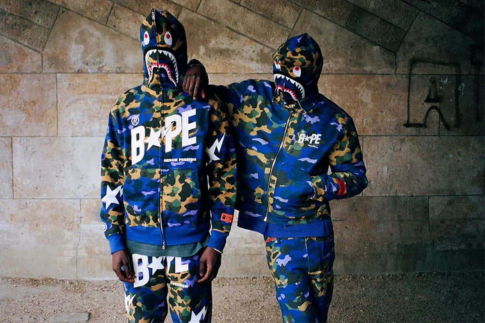 Bape 動態 桌布 壁紙 — 兩個人穿著藍色迷彩Bape鯊魚連帽衫在帶有塗鴉的石拱門下擺姿勢。