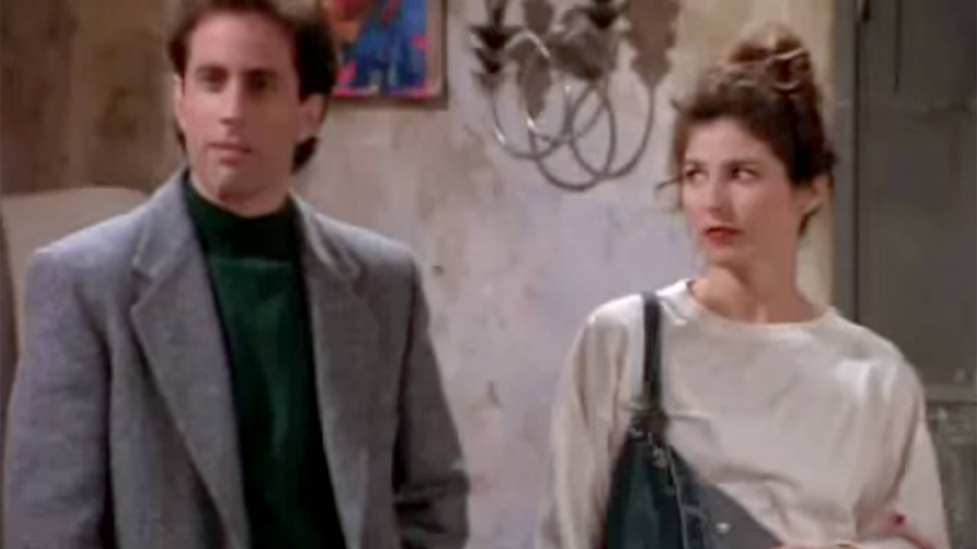Seinfeld 桌布 壁紙 — 兩個人站在一個光線昏暗的房間裡，房間裡有吊燈和牆上的藝術品。