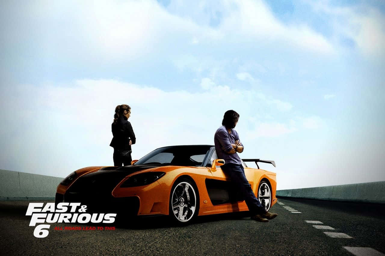 Best Fast And Furious 桌布 壁紙 — 兩個人自信地站在一輛充滿活力的橙色跑車旁邊，在開闊的高速公路上，天空明亮。