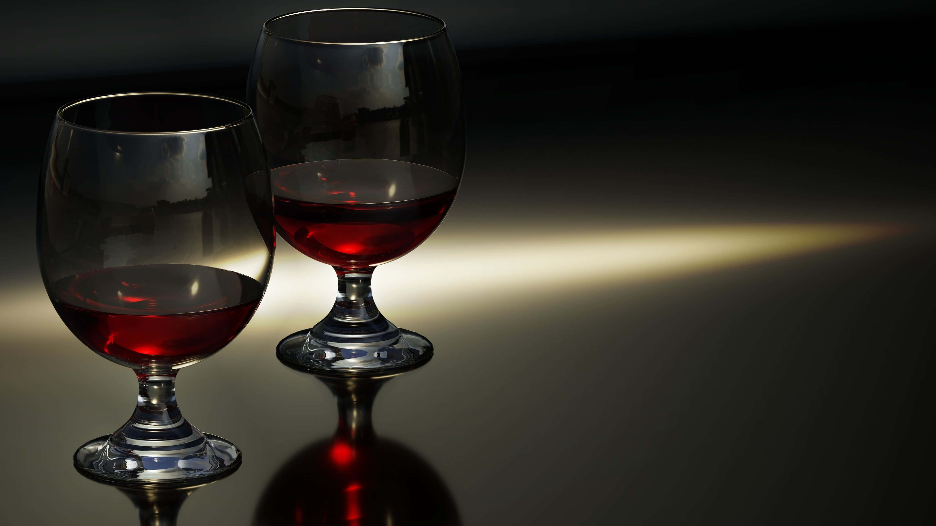 Red Wine Glass 桌布 壁紙 — 兩個優雅的紅色液體玻璃杯在聚光燈下在反光的深色表面上閃耀。
