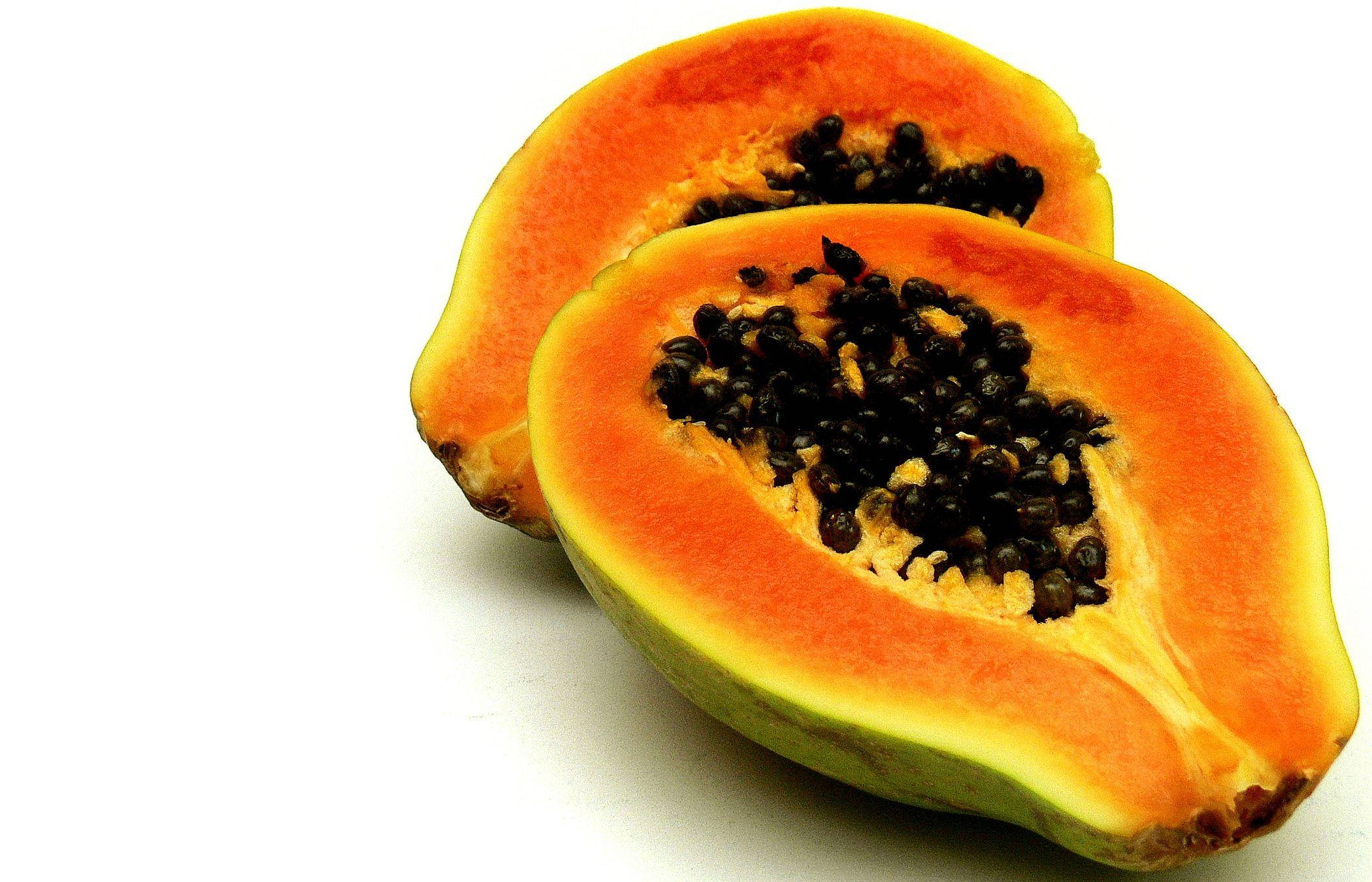 Fruits 桌布 壁紙 — 兩個充滿活力的半切木瓜，帶有多汁的橙色果肉和黑色種子，放在純白色背景上。