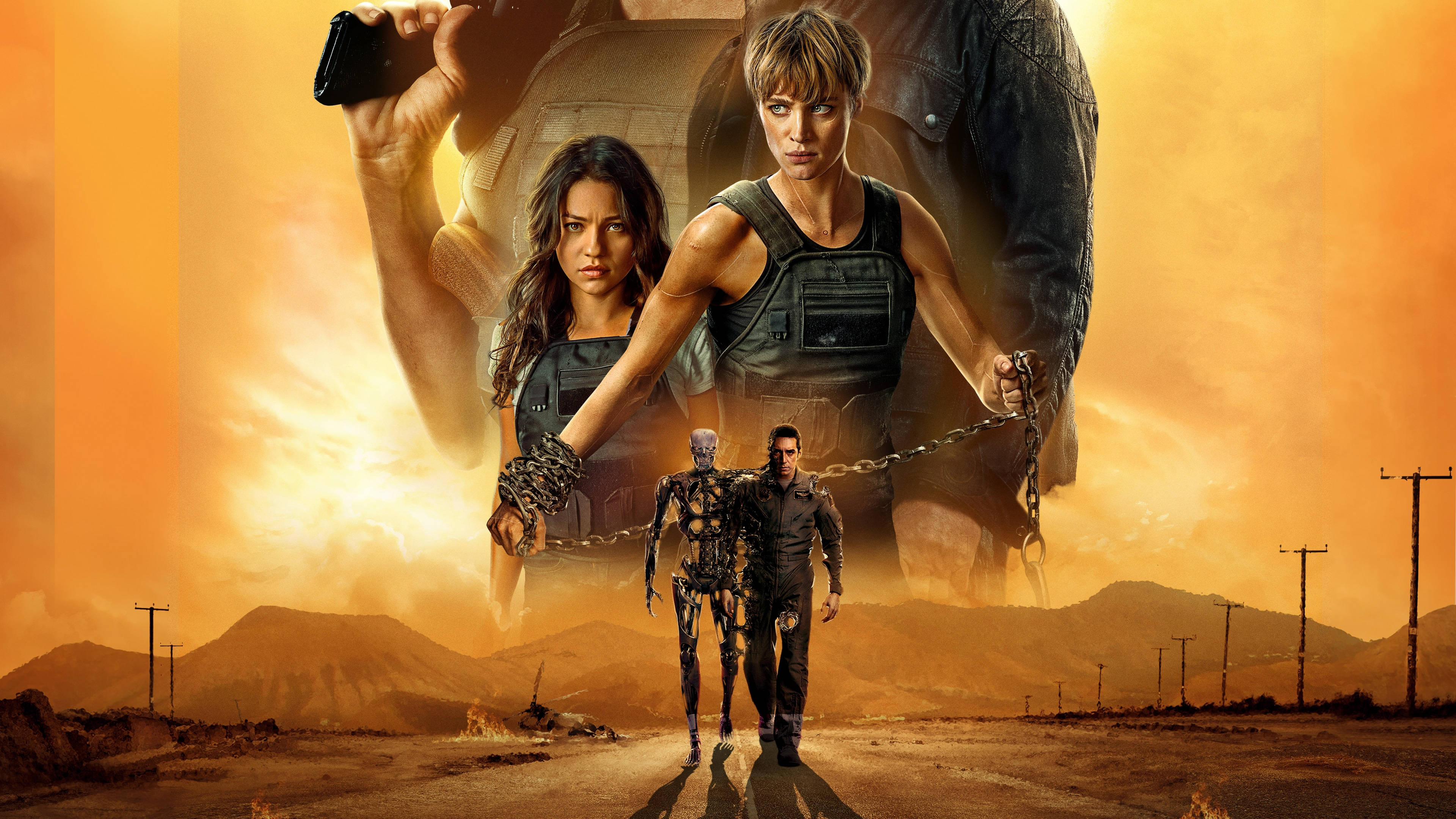 Terminator 4K 桌布 壁紙 — 兩個兇猛的女人和一個男人帶著機器人同伴，在熾熱的橙色天空下走過塵土飛揚的沙漠。