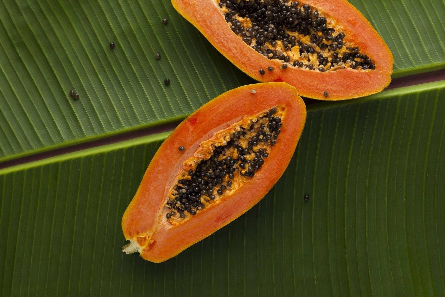 Fruits 桌布 壁紙 — 兩個切半的番石榴帶有黑色種子，放在大片綠色香蕉葉上，展現出充滿活力的熱帶質感。