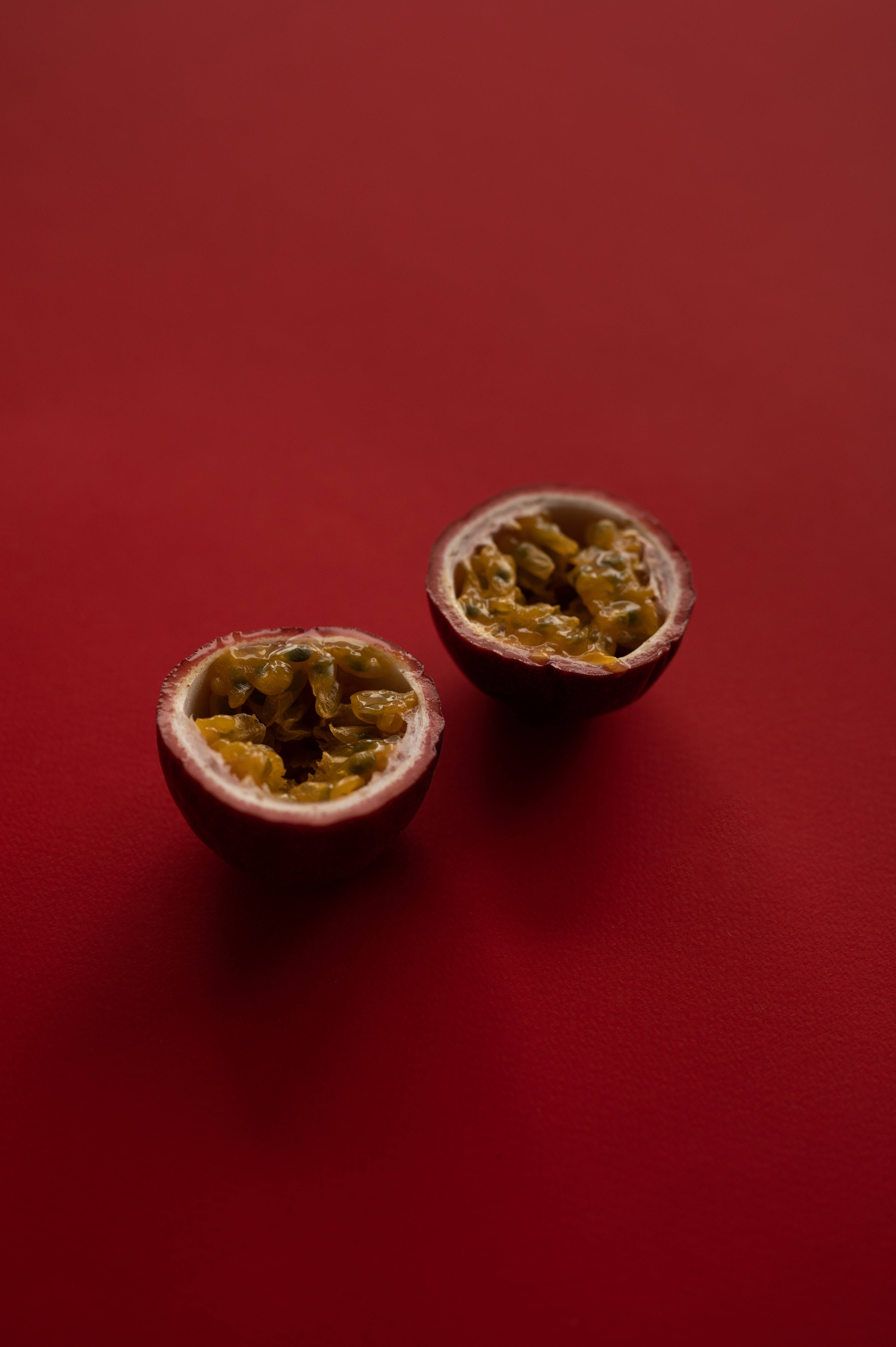 Fruits 桌布 壁紙 — 兩個切半的百香果在濃郁的紅色背景下展現出多汁的黃色果肉。
