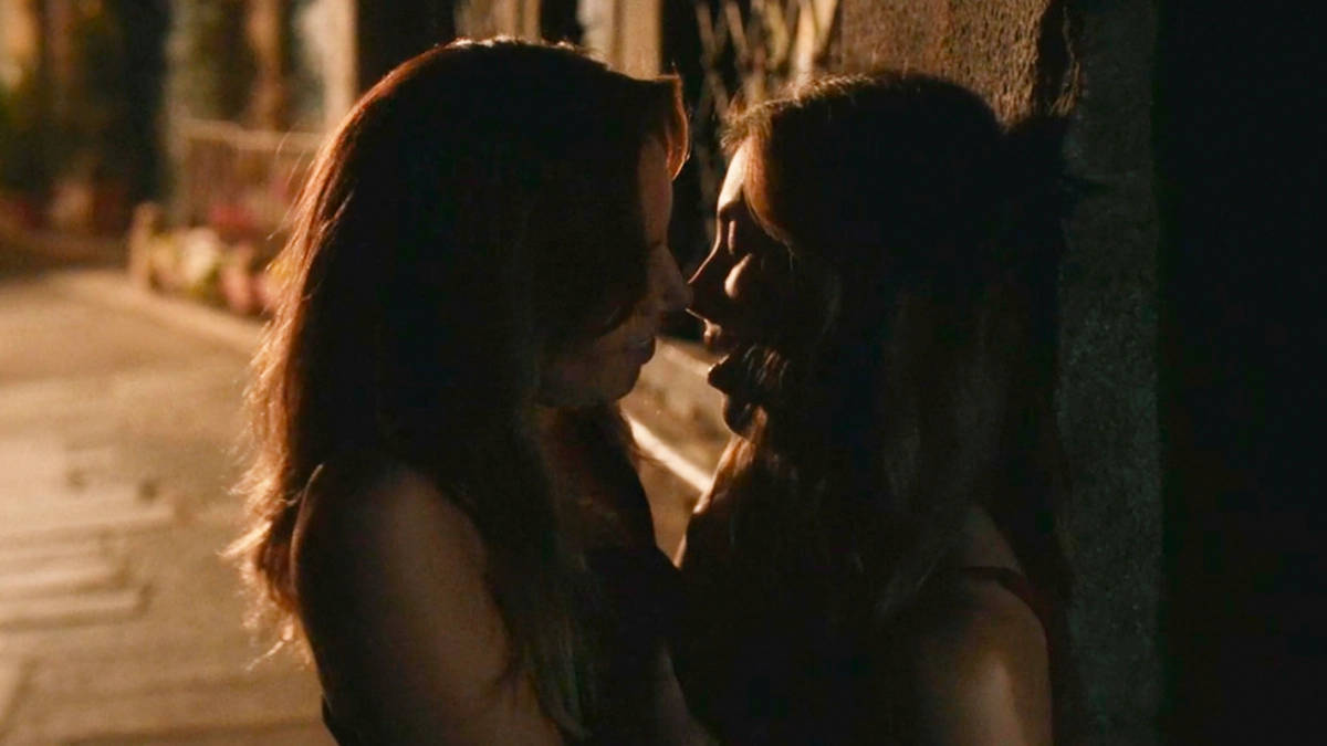 Kissing 桌布 壁紙 — 兩個剪影中的女性在夜晚寧靜的城市小巷中，在溫暖的路燈下分享親密時刻。