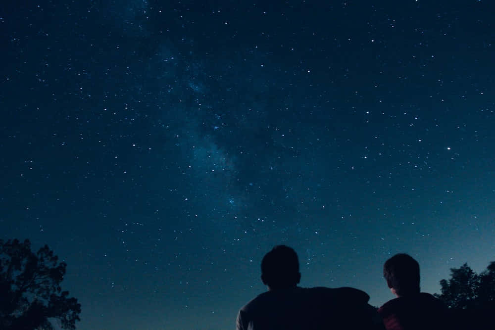 Stars 桌布 壁紙 — 兩個剪影人物仰望令人嘆為觀止的星空，銀河在他們上方閃耀。