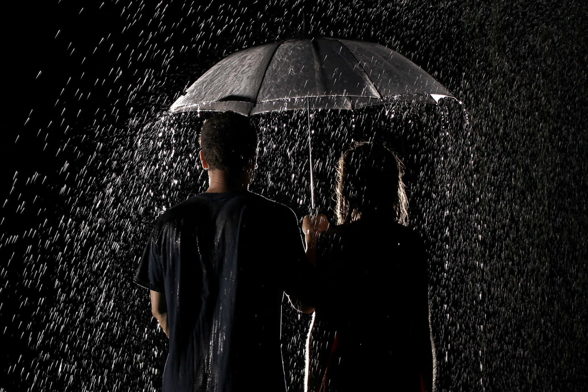 Umbrella 桌布 壁紙 — 兩個剪影人物共用一把雨傘，雨水在漆黑背景中傾瀉而下。
