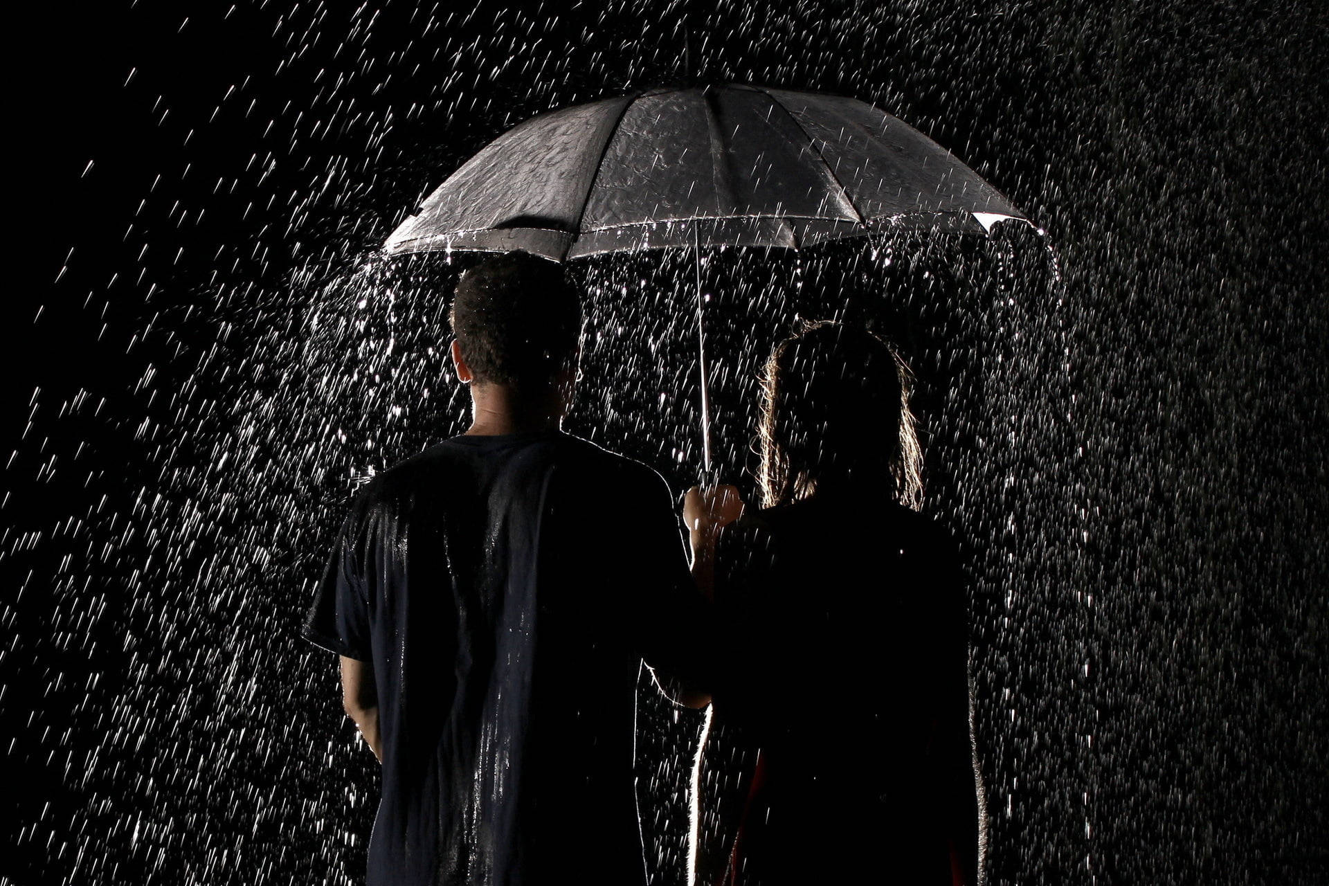 情侶 桌布 壁紙 — 兩個剪影人物共用一把雨傘，雨水在漆黑背景上傾瀉而下。