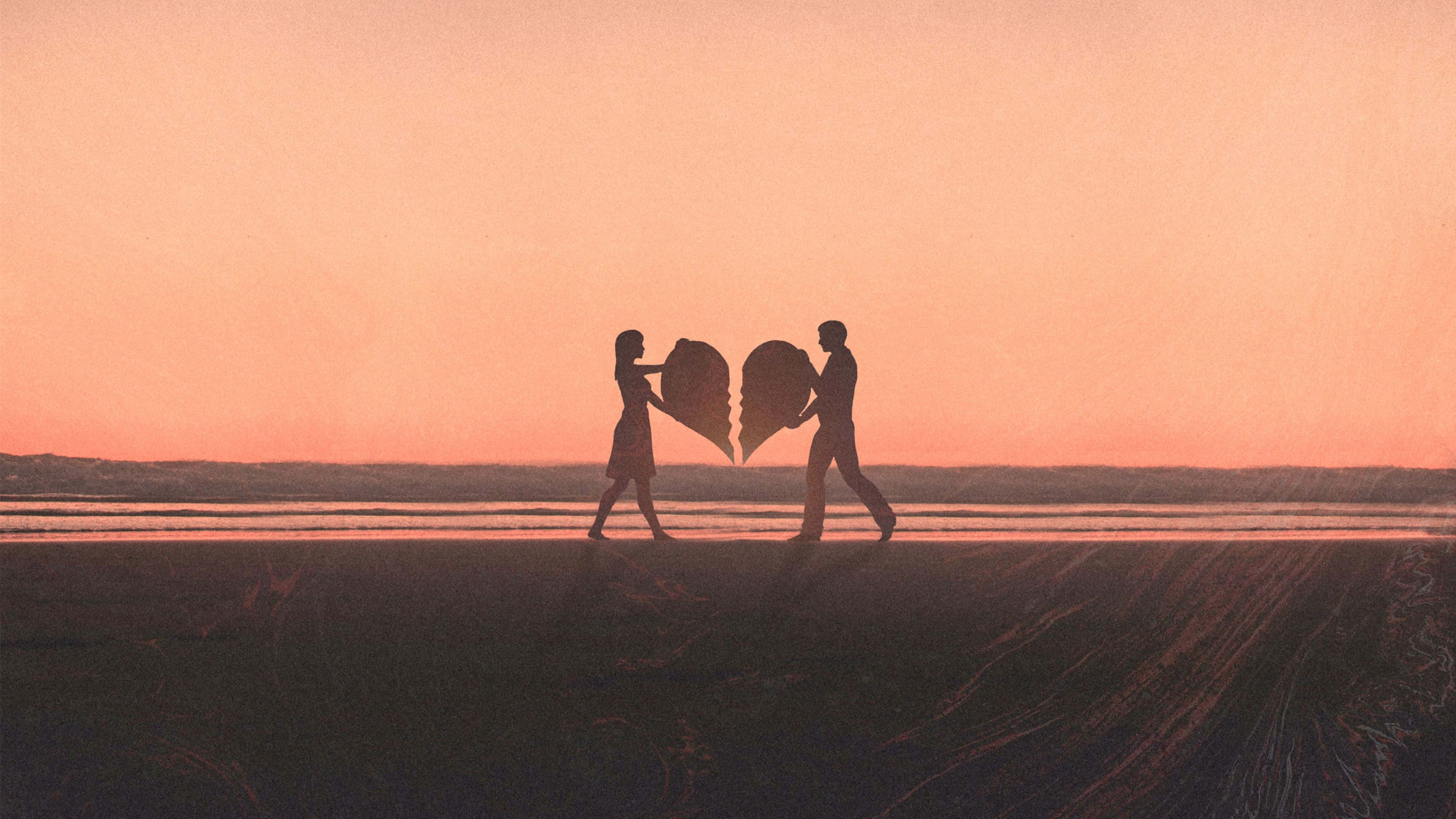 couple love 桌布 壁紙 — 兩個剪影人物在日落時沿著海灘行走，每人拿著半個破碎的心。
