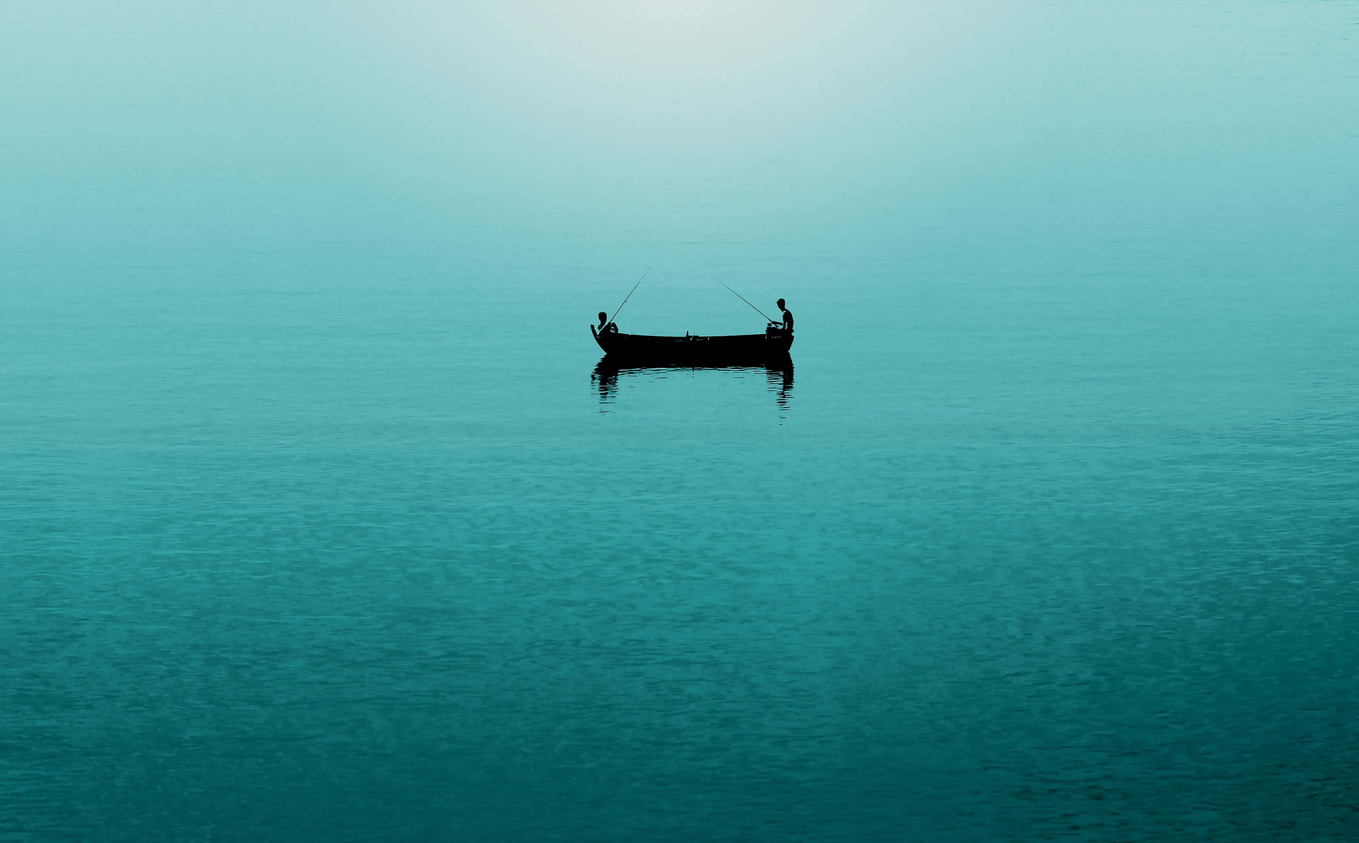 Minimalist Ocean 桌布 壁紙 — 兩個剪影人物在朦朧的天空下，從一艘小船在廣闊平靜的藍綠色海面上釣魚。