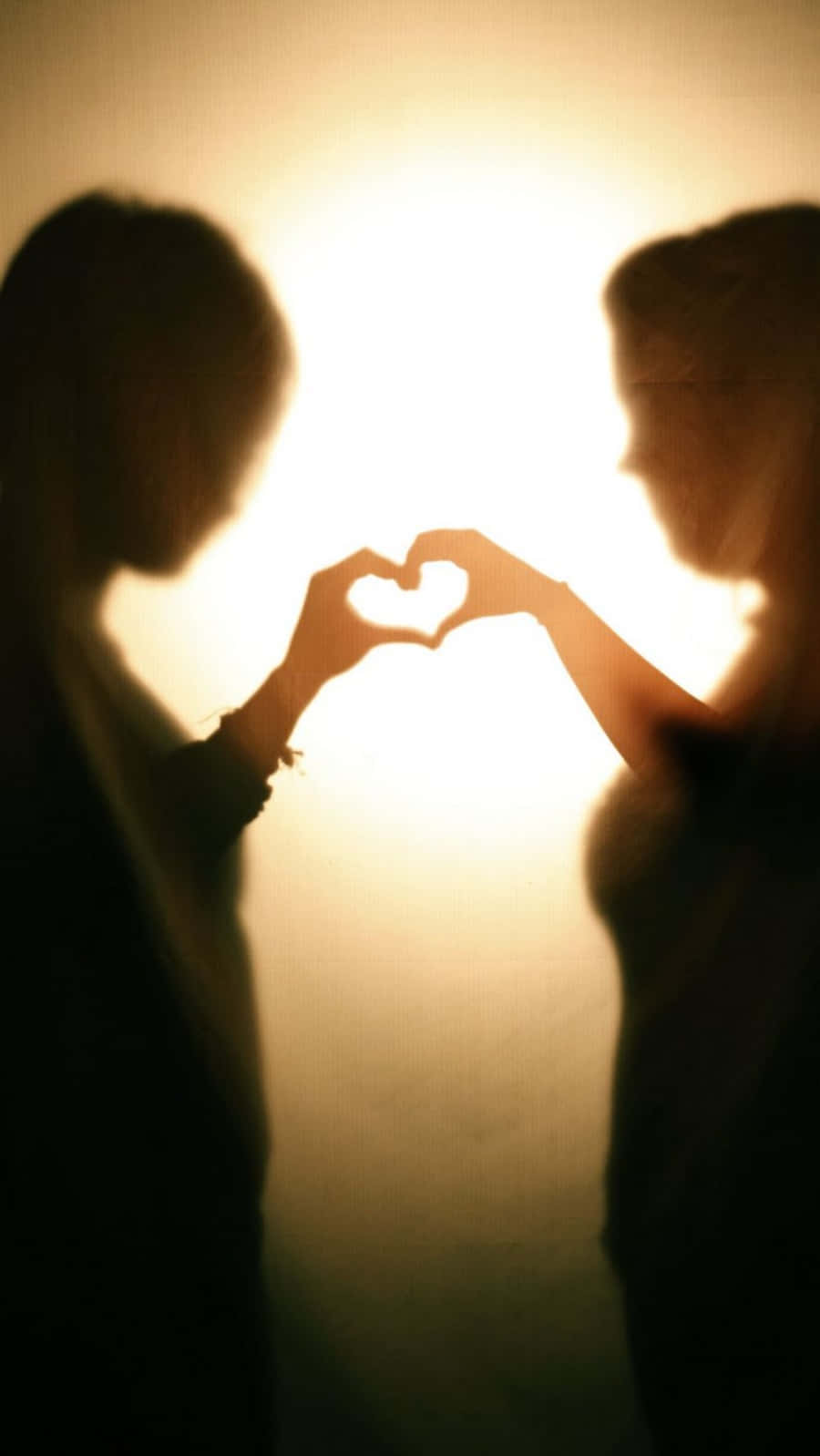 Heart Silhouette 桌布 壁紙 — 兩個剪影人物用雙手形成心形，背景是溫暖發光的逆光。