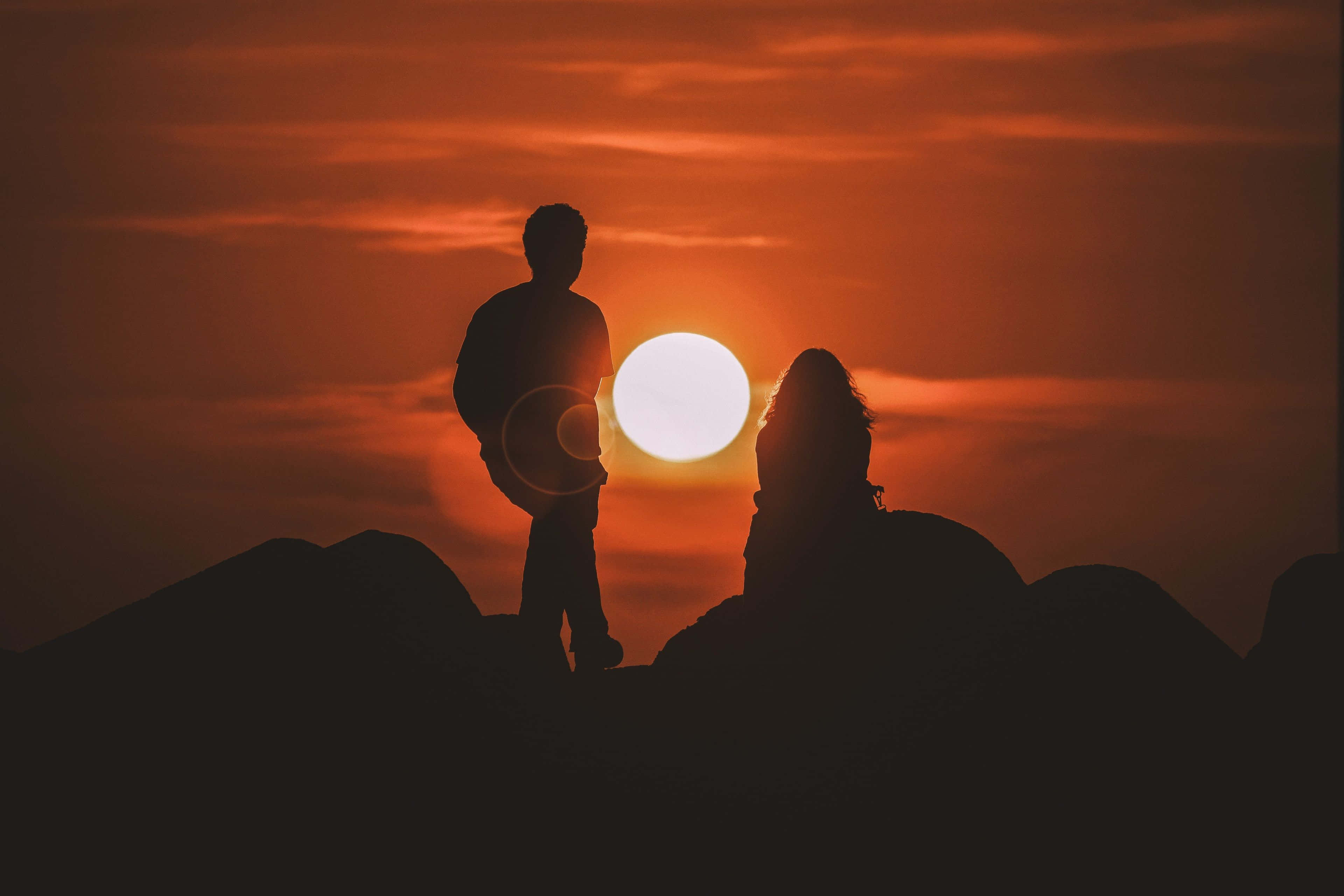 couple love 桌布 壁紙 — 兩個剪影人物站在山脊頂部，觀看身後發光的夕陽。