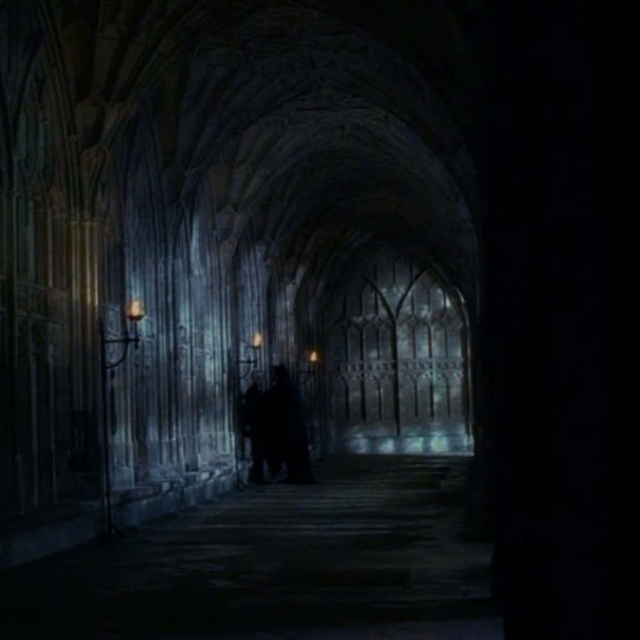 The Hogwarts Forbidden Corridor 桌布 壁紙 — 兩個剪影人物站在昏暗的哥德式大教堂走廊中，由閃爍的牆上火把照亮。