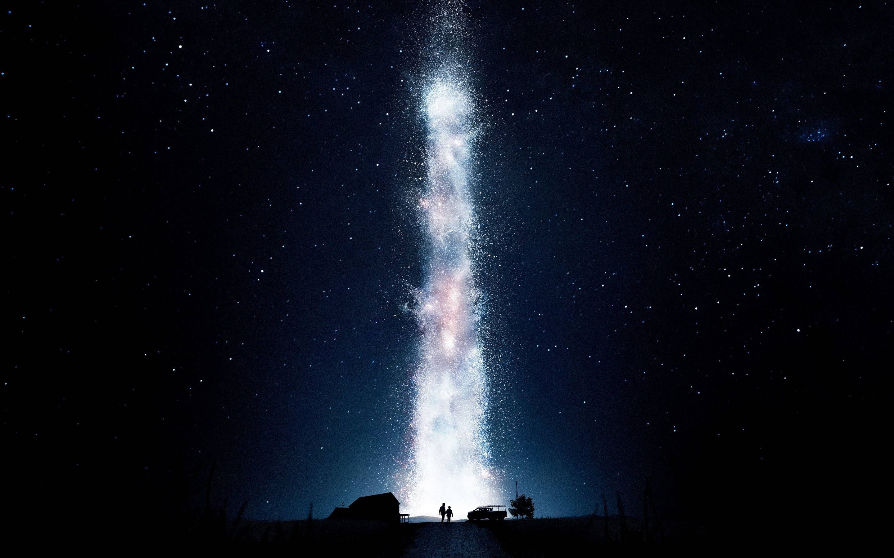星際效應 桌布 壁紙 — 兩個剪影人物站在高聳、發光的銀河系下方，銀河系垂直延伸在繁星點點的夜空。