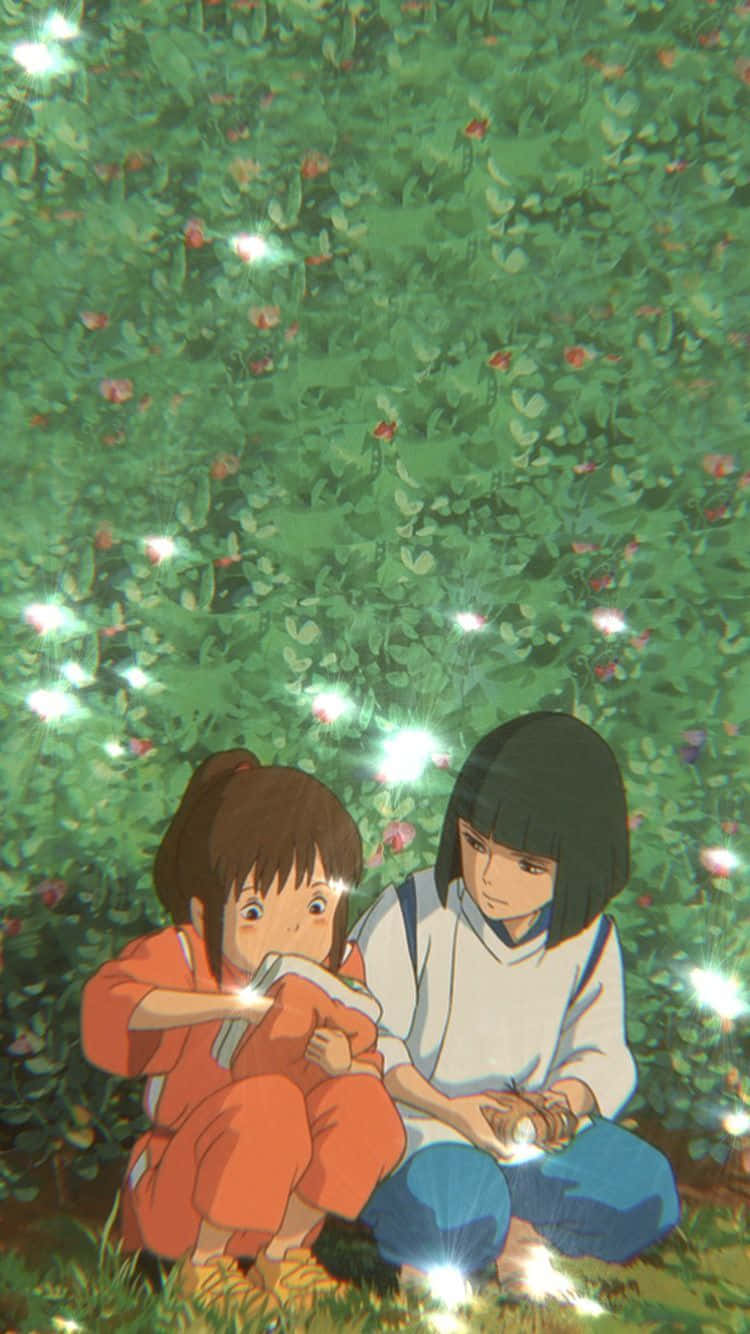 Haku Spirited Away Phone 桌布 壁紙 — 兩個動漫女孩坐在發光的綠色花田中，手持燈籠，柔和的光芒在她們周圍閃爍。