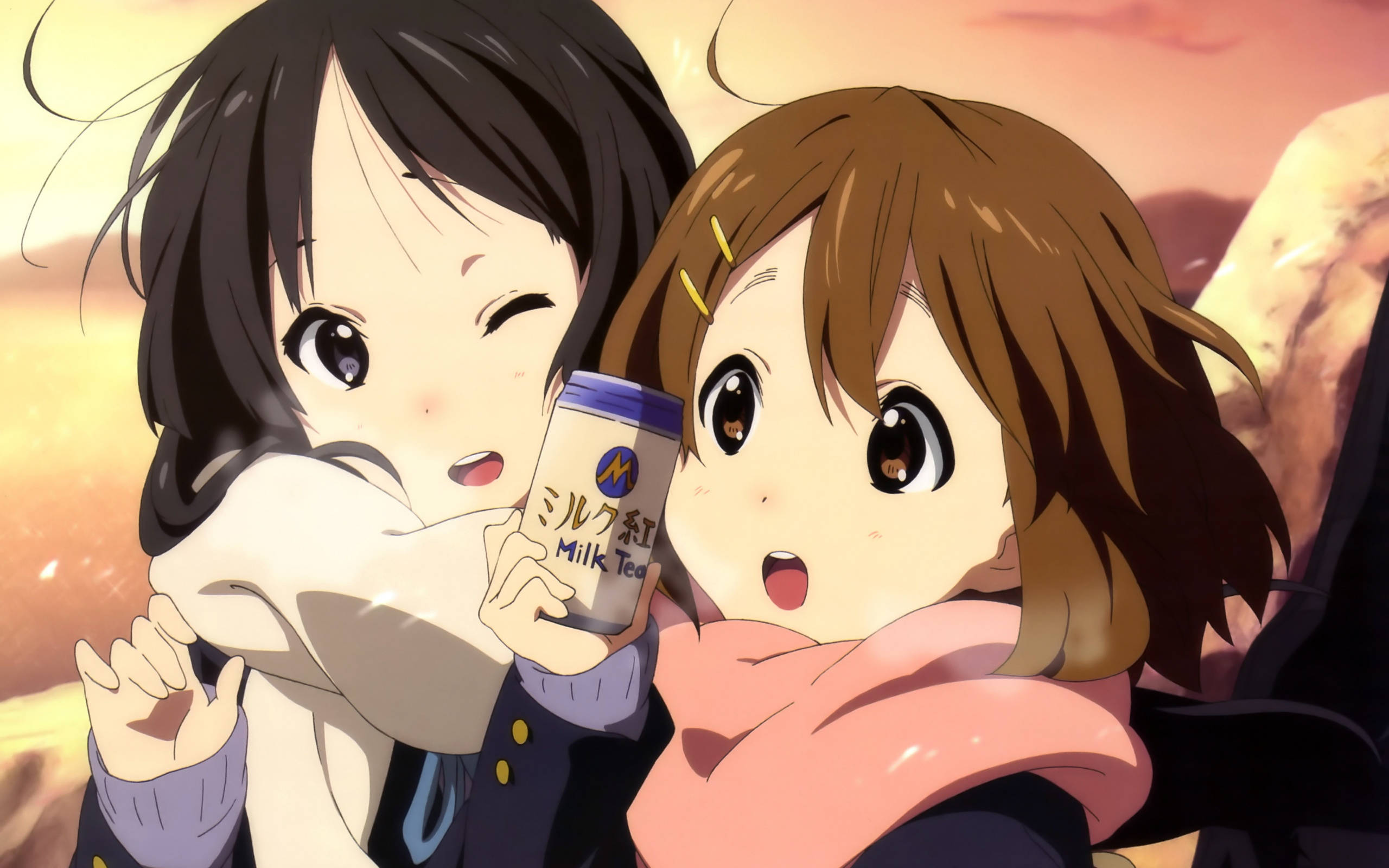 K-on 桌布 壁紙 — 兩個動漫女孩擁抱，其中一個拿著一杯奶茶，背景是溫暖的日落。
