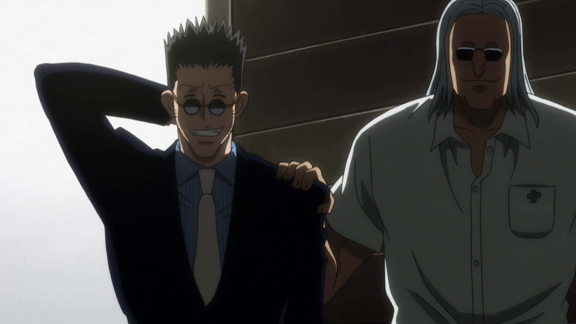 Leorio Paradinight 桌布 壁紙 — 兩個動漫男人，一個穿著西裝微笑，手放在腦後，另一個穿著白襯衫和太陽眼鏡並排站立。