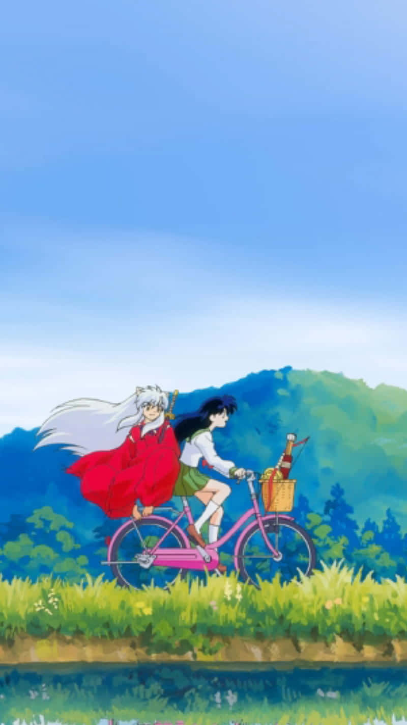 Inuyasha iPhone 桌布 壁紙 — 兩個動漫角色在晴朗藍天下，騎著粉紅色自行車穿過充滿活力的綠色田野。