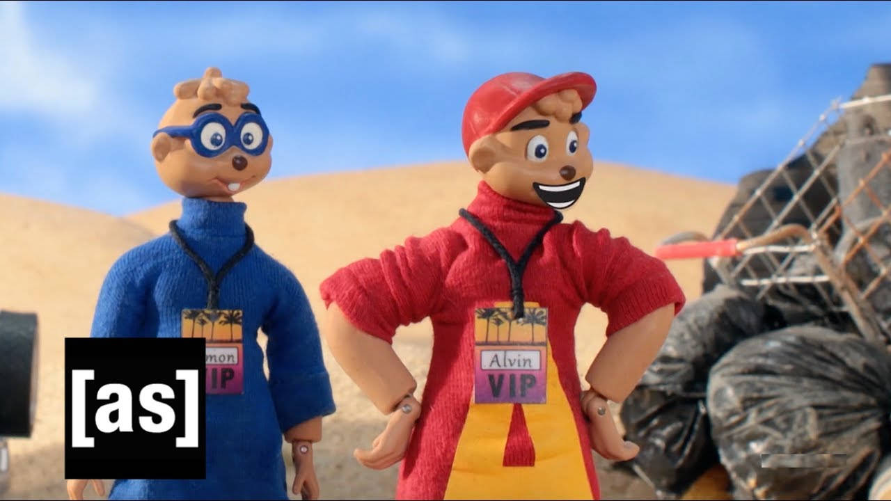 Animated 桌布 壁紙 — 兩個動畫花栗鼠角色穿著色彩繽紛的服裝，在晴朗的藍天下自信地站在沙漠垃圾場中。