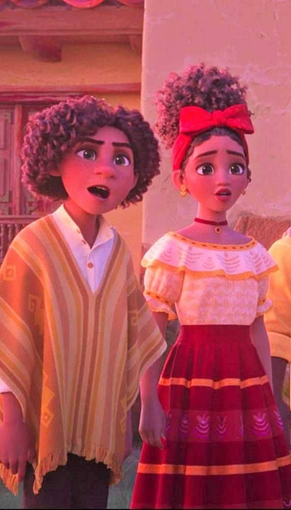 Encanto Camilo 桌布 壁紙 — 兩個動畫角色穿著鮮豔的傳統墨西哥服飾，在溫暖照明的庭院中並肩站立，表情驚訝。