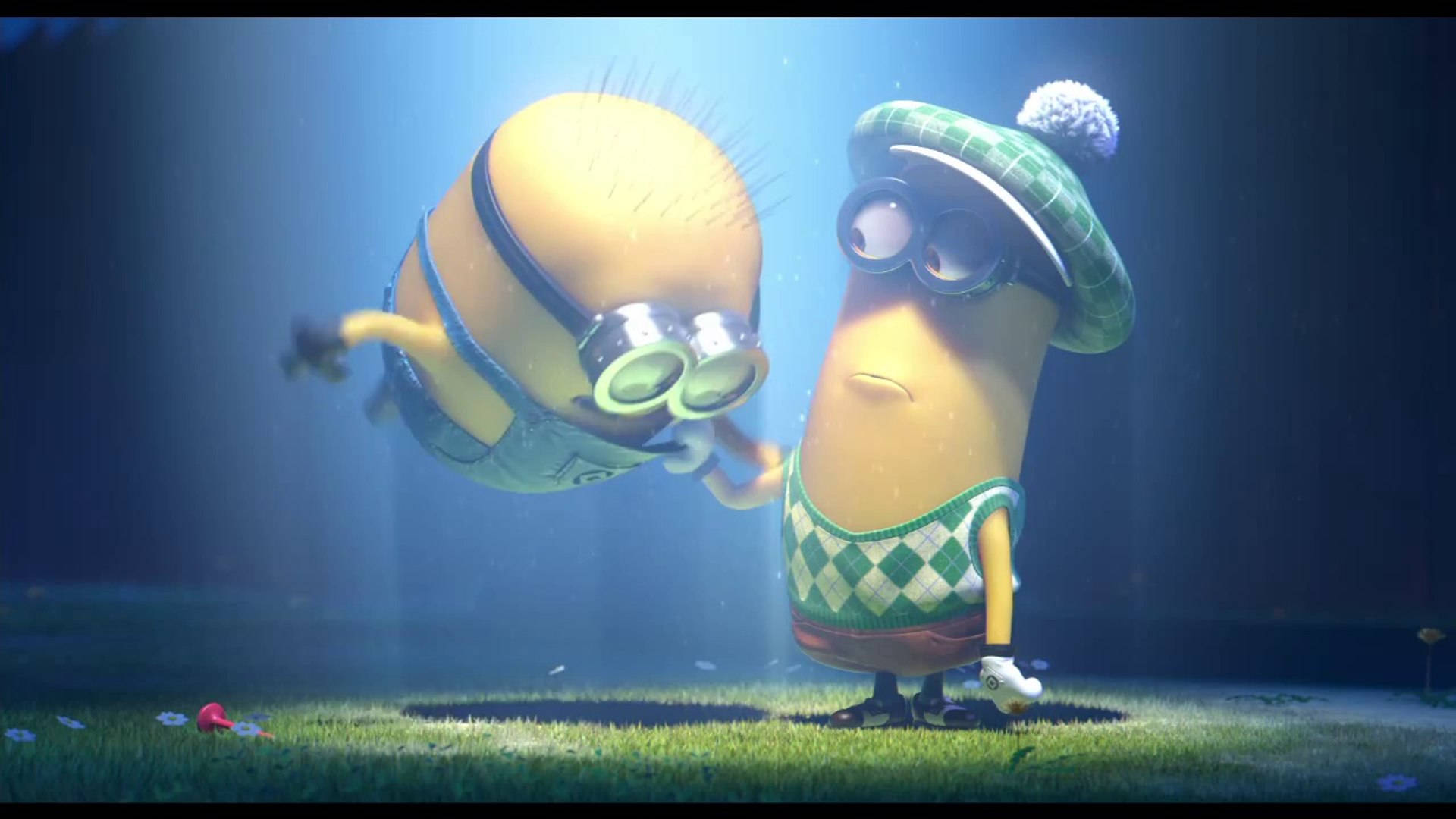 Despicable Me 2 桌布 壁紙 — 兩個動畫黃色 minions，一個穿著綠色格紋服裝和帽子，另一個在半空中漂浮，兩者都在藍色聚光燈下，站在草地上。