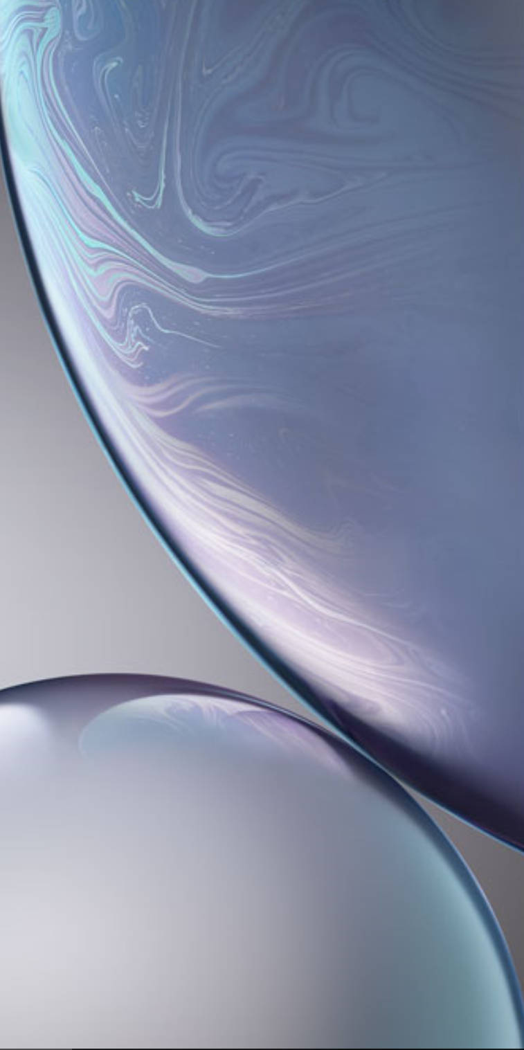 iPhone XS 桌布 壁紙 — 兩個半透明玻璃球體，帶有旋轉的彩虹色圖案，漂浮在柔和的灰色背景上。