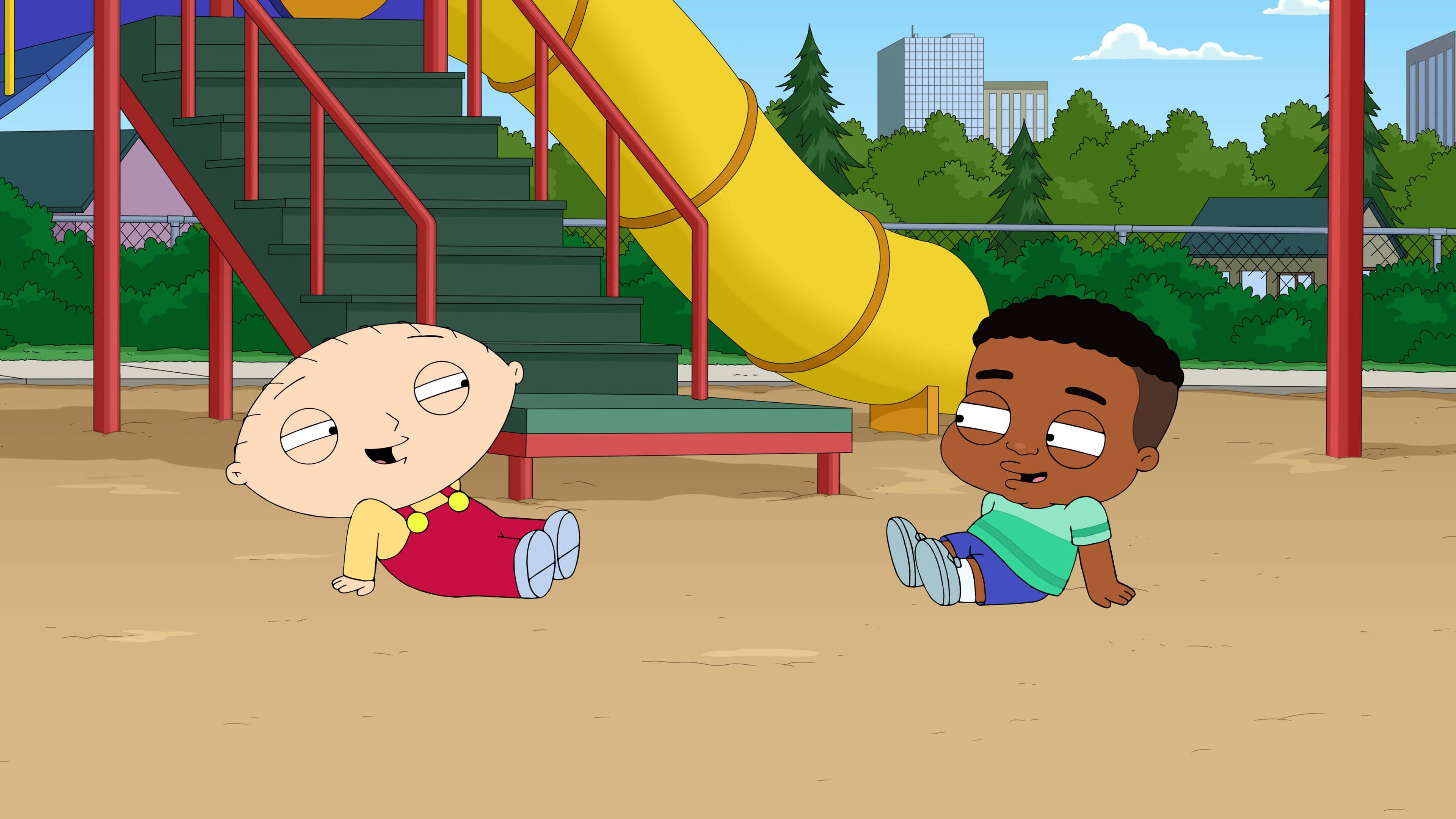 stewie 桌布 壁紙 — 兩個卡通幼兒坐在沙地上，靠近一個黃色溜滑梯，背景是陽光明媚的遊樂場，有綠樹和城市建築。