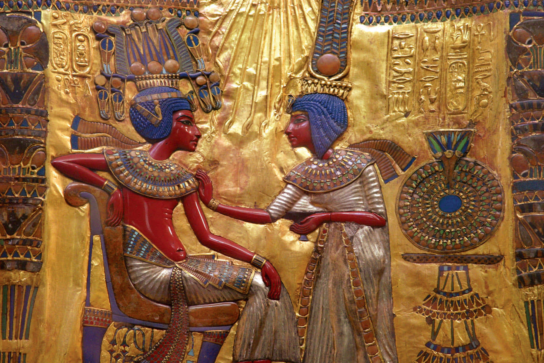 egyptian 桌布 壁紙 — 兩個古埃及人物穿著鮮豔的紅色和金色服飾，在鍍金象形文字背景前進行儀式互動。